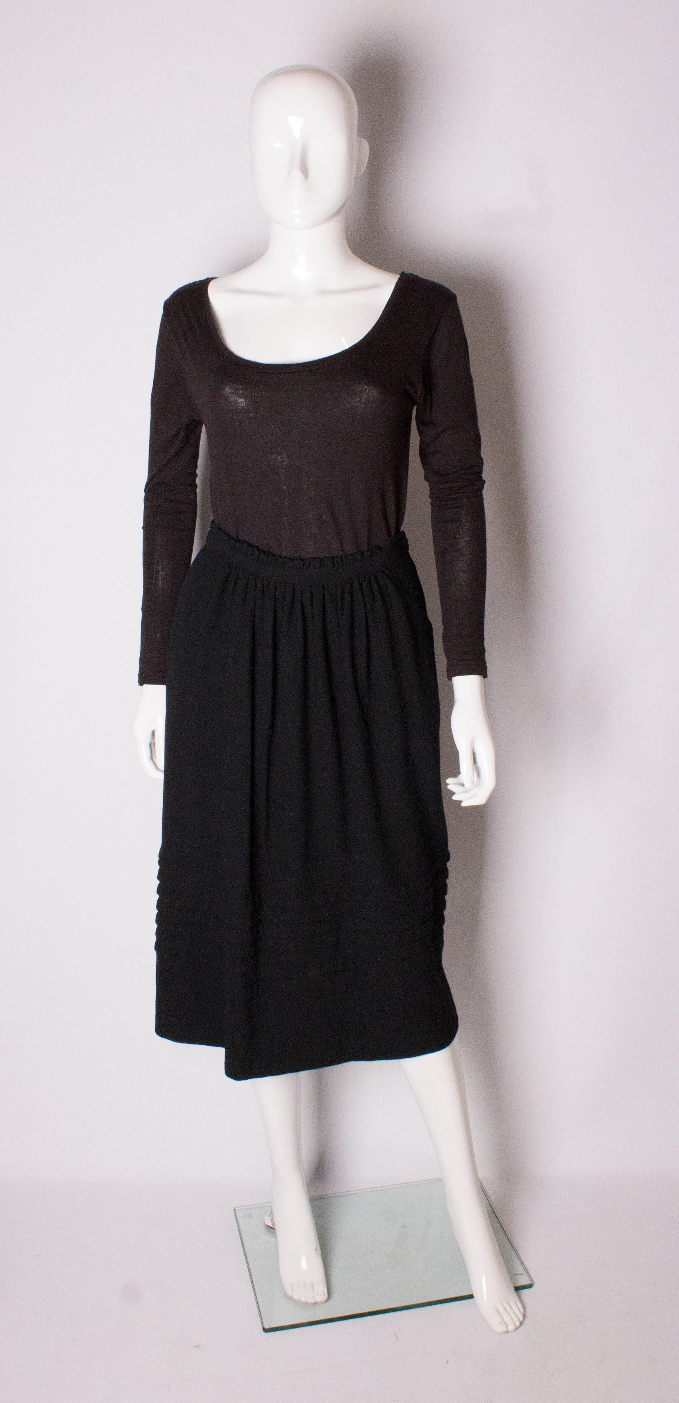 A chic and warm skirt by Christian Dior. The black wool skirt is fully lined, has gathering at the waist and rows of pleats near the hem. The skirt has a zip on the left hand side and pockets.