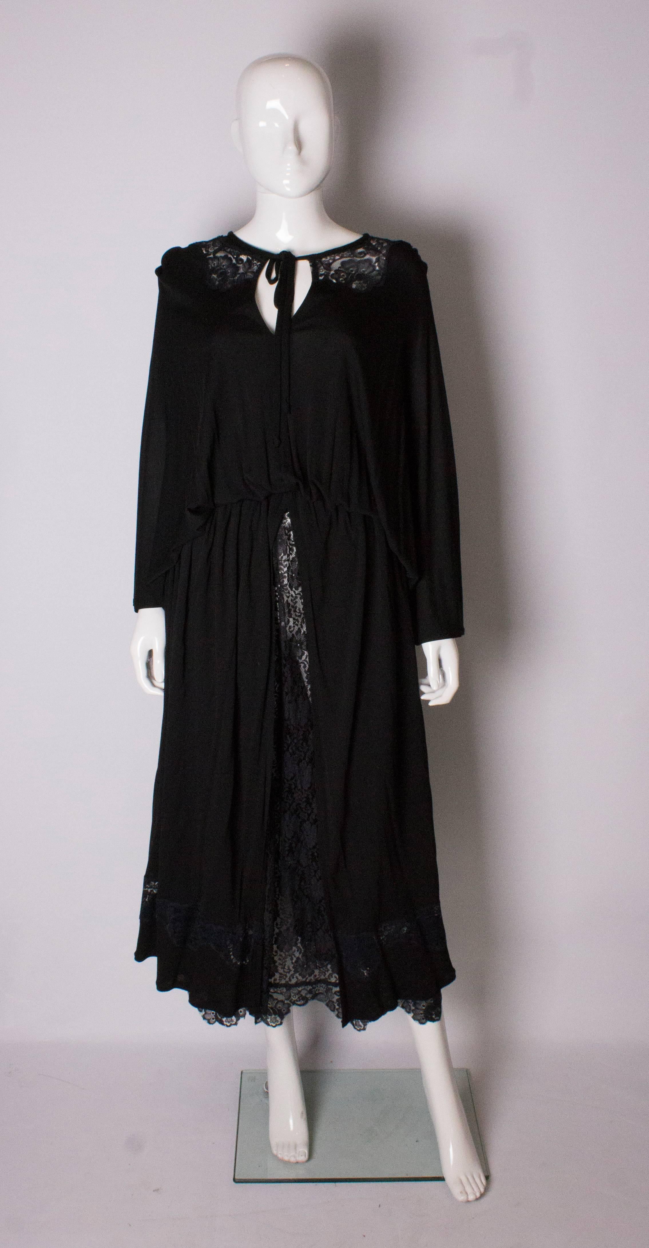 An evening dress by Quorum. The dress has a lace collar and skirt , with a black split over skirt. There is a row of lace at the hem.