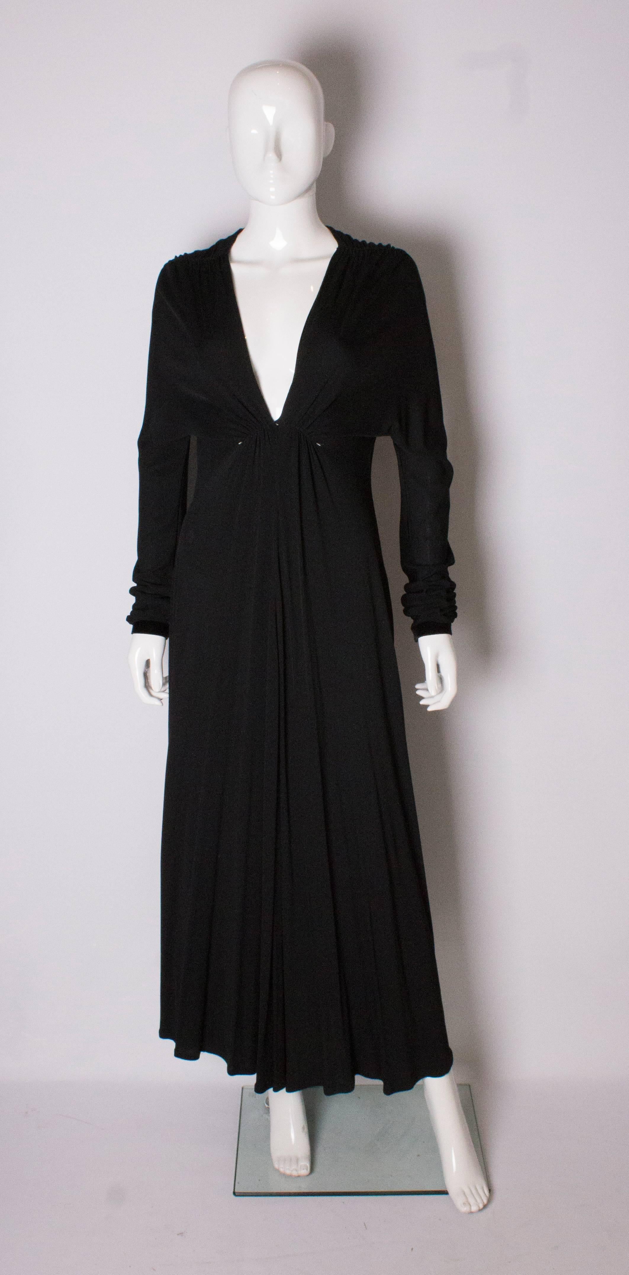 A chic black evening gown by Yves Saint Laurent Rive Gauche. The dress has a v neckline ,pleats at the shoulders and gathering under the bust. The cuffs and neckline are trimmed in black velvet.