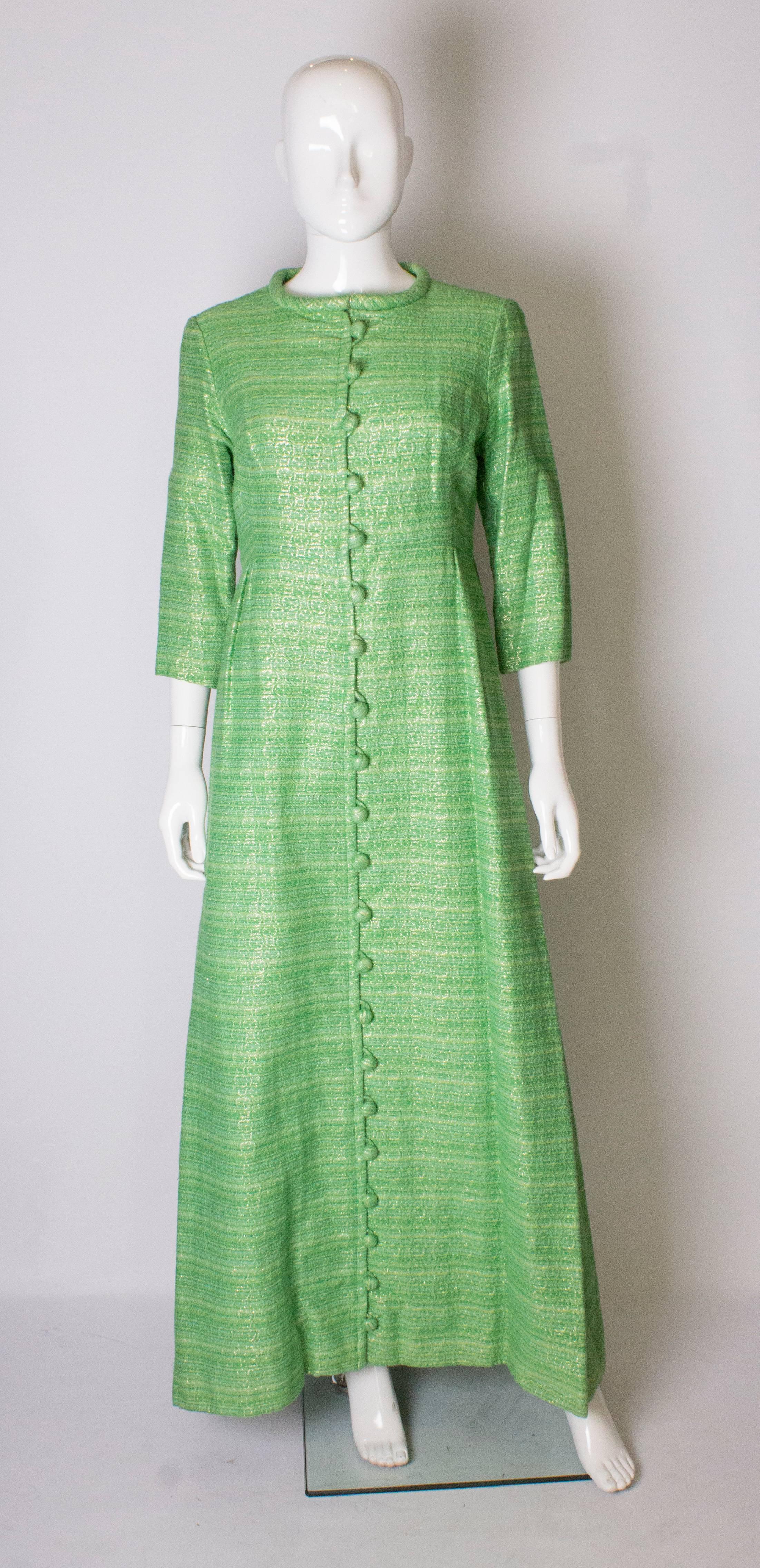 A chic green coat dress  by Pierre Celeyre. The coat dress has a round neck , elbow length sleeve, and gathering at the waist. It is fully lined.