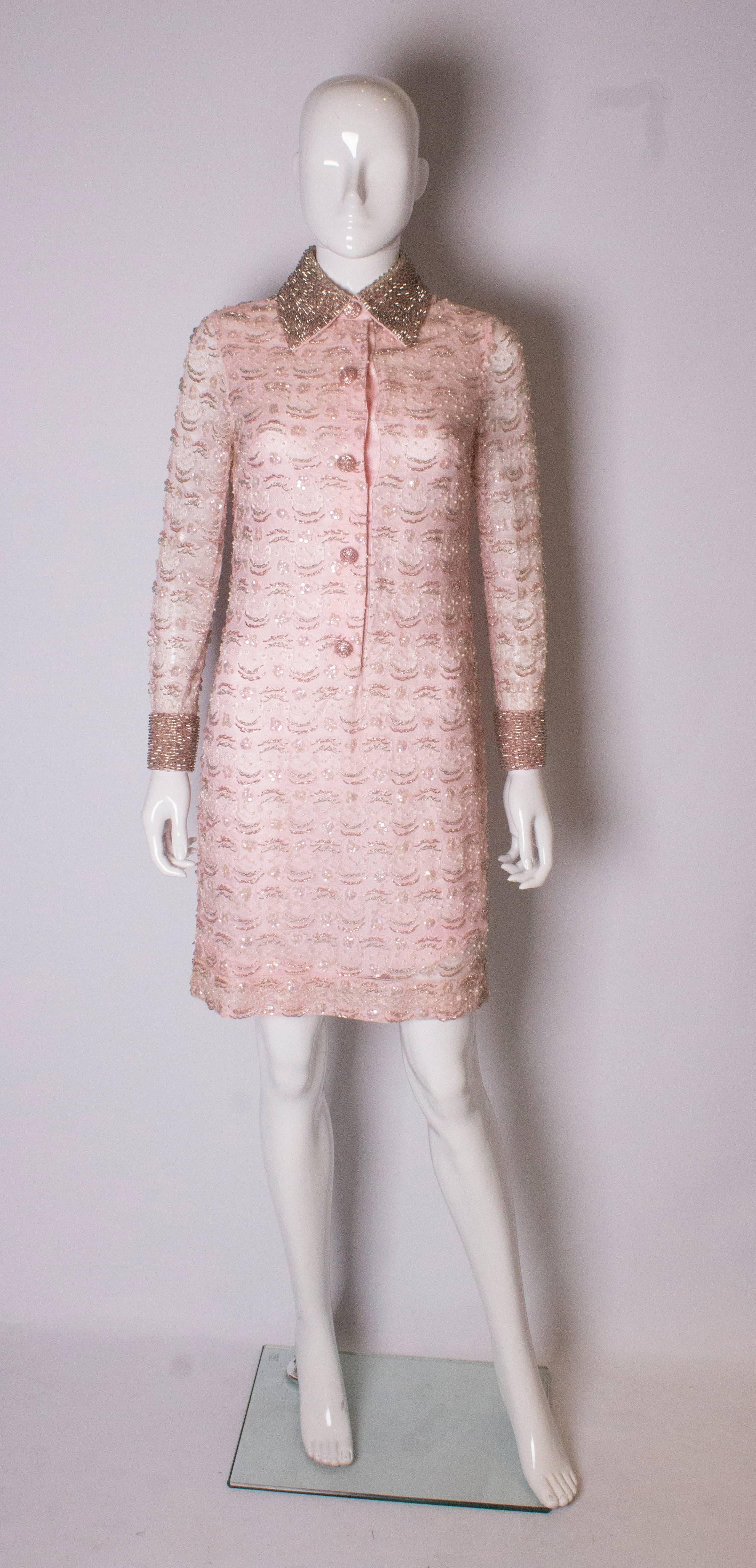 A chic pink shirt dress, in lace with bead decoration. The dress is fully lined, and has a beaded collar and cuffs. It opens with 5 buttons with poppers.