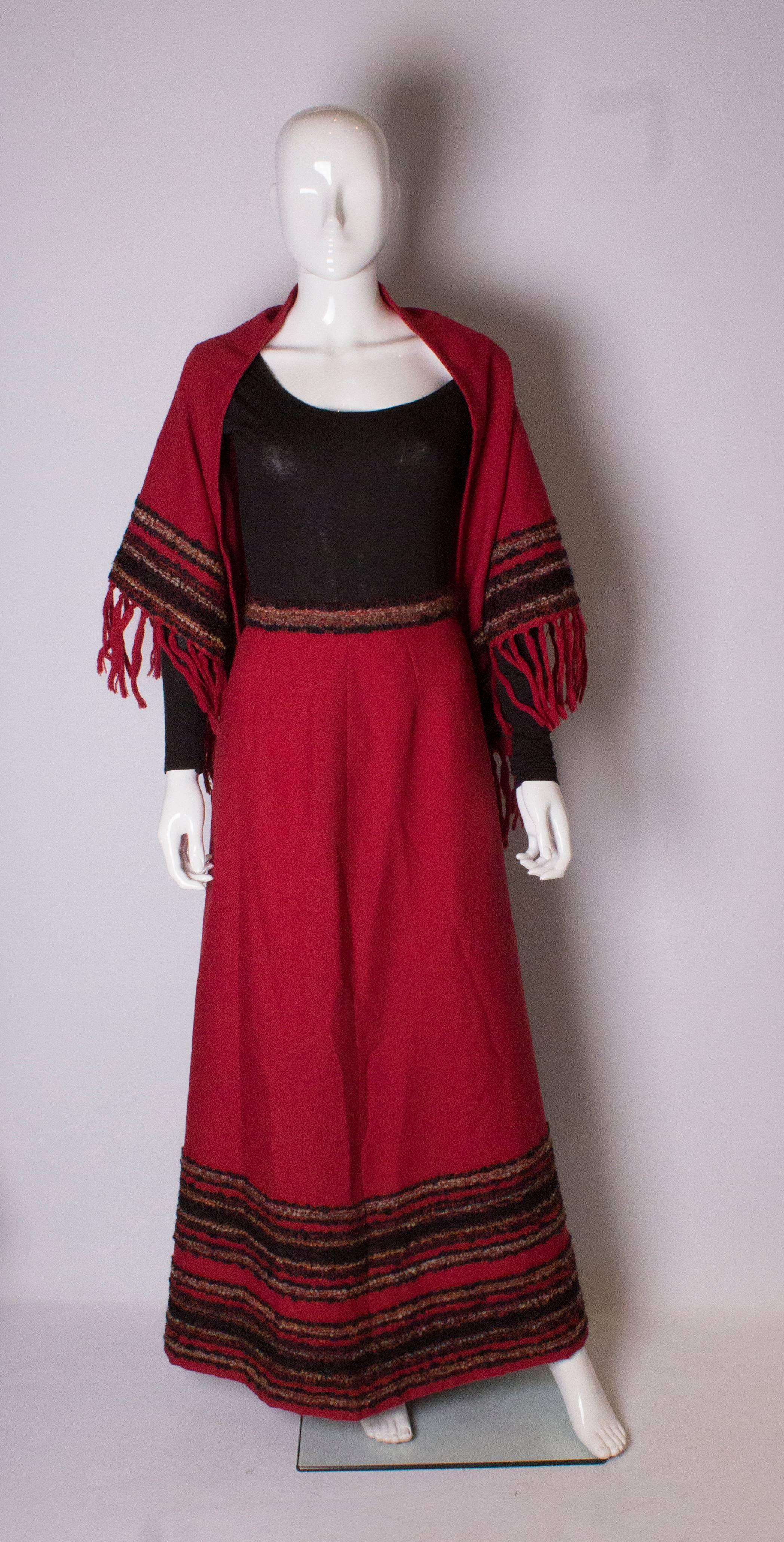 A lovely red wool mix ( 85% wool, 10% polymaid, 5% viscose)  skirt with matching shawl by Arola of Finland.
The skirt has detail on the waist band and hem, and is fully lined.
The shawl has the same detail.