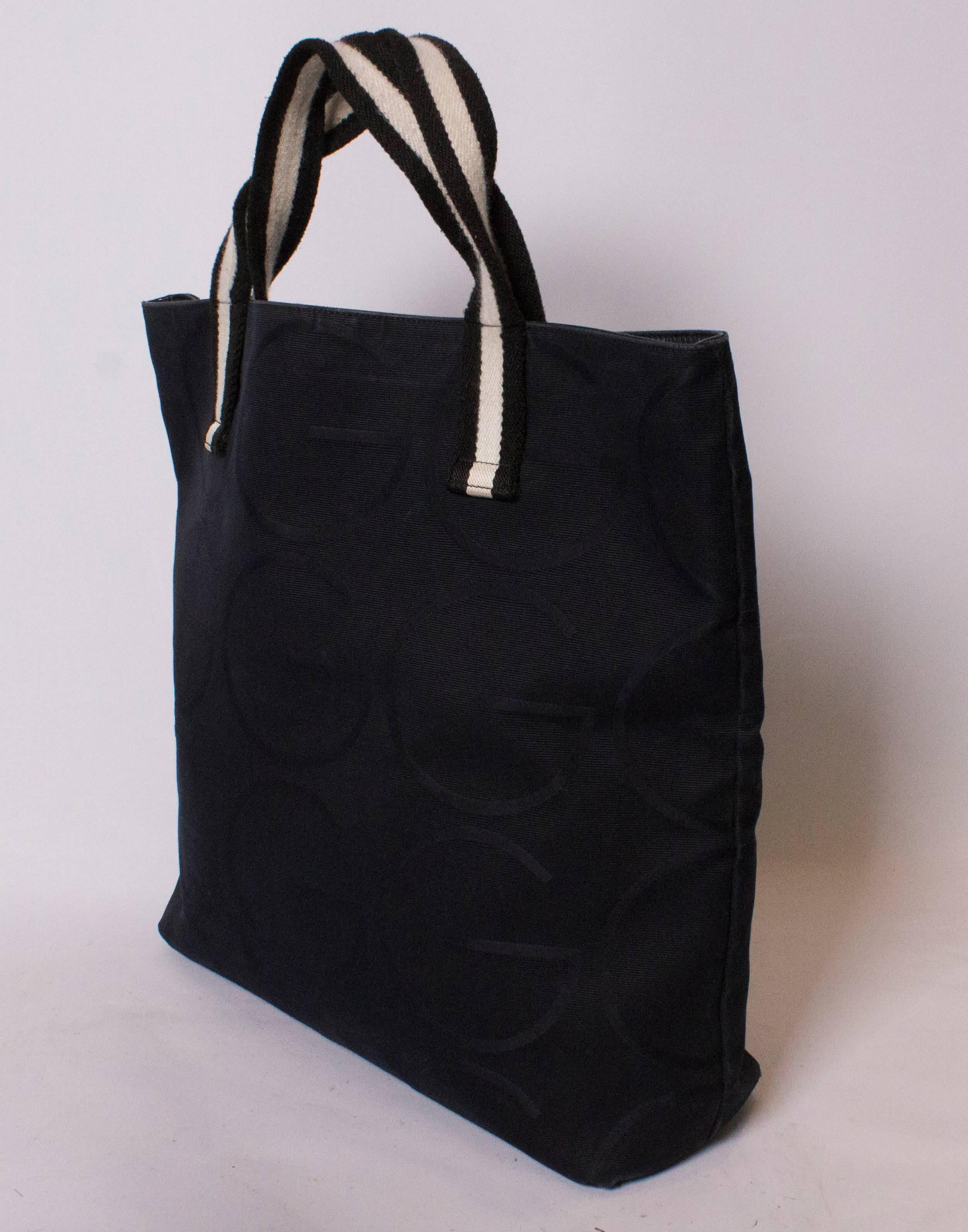 A black Gucci shopper, with black and white handles. The black fabric has the letter G woven in, and the serial number is 128 439/002058.There is an internal pouch pocket, and the measurements are: Base 15 1/2'' x 4'', and height 16''.