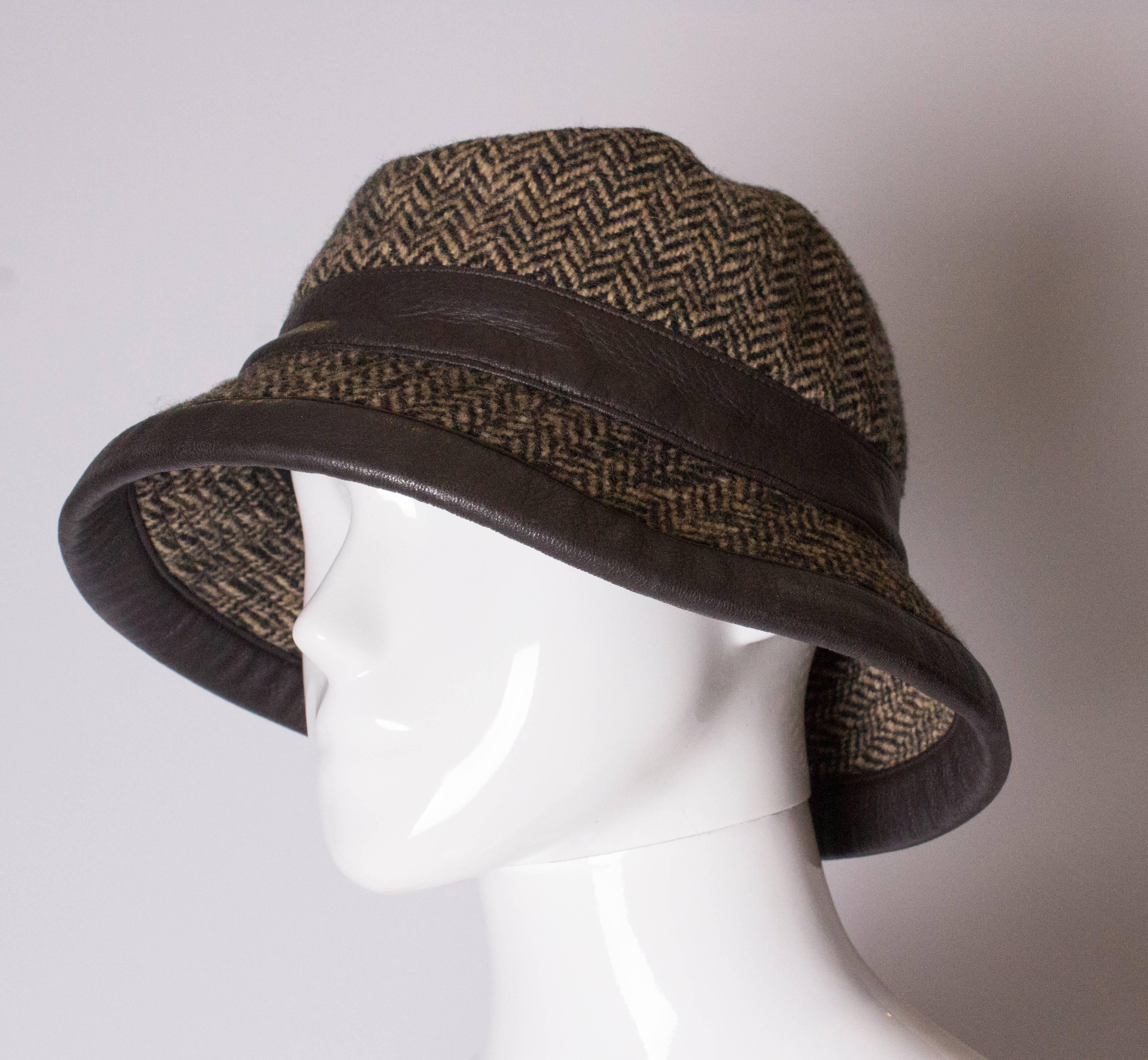 A chic wool and cashmere hat by Hermes -90%wool, 10% cashmere.The hat is in a herringbone design, in shades of brown with leather trim. It is fully lined. The hat has a leather band at the base of the crown and another at the edge of the brim. It is