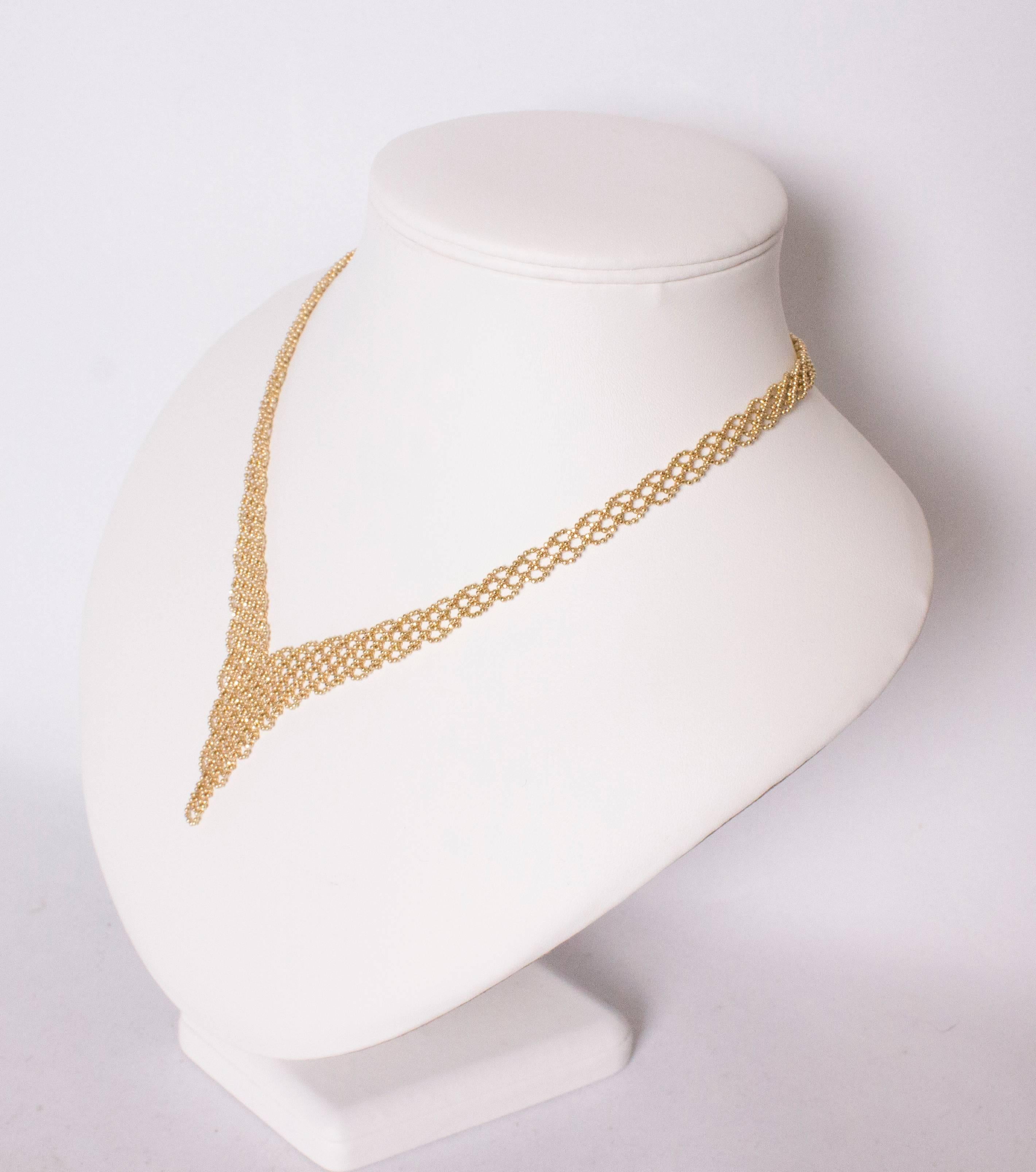 A chic gold necklace in mesh work , with a pointed centre. The necklace is 20'' in length, and 
