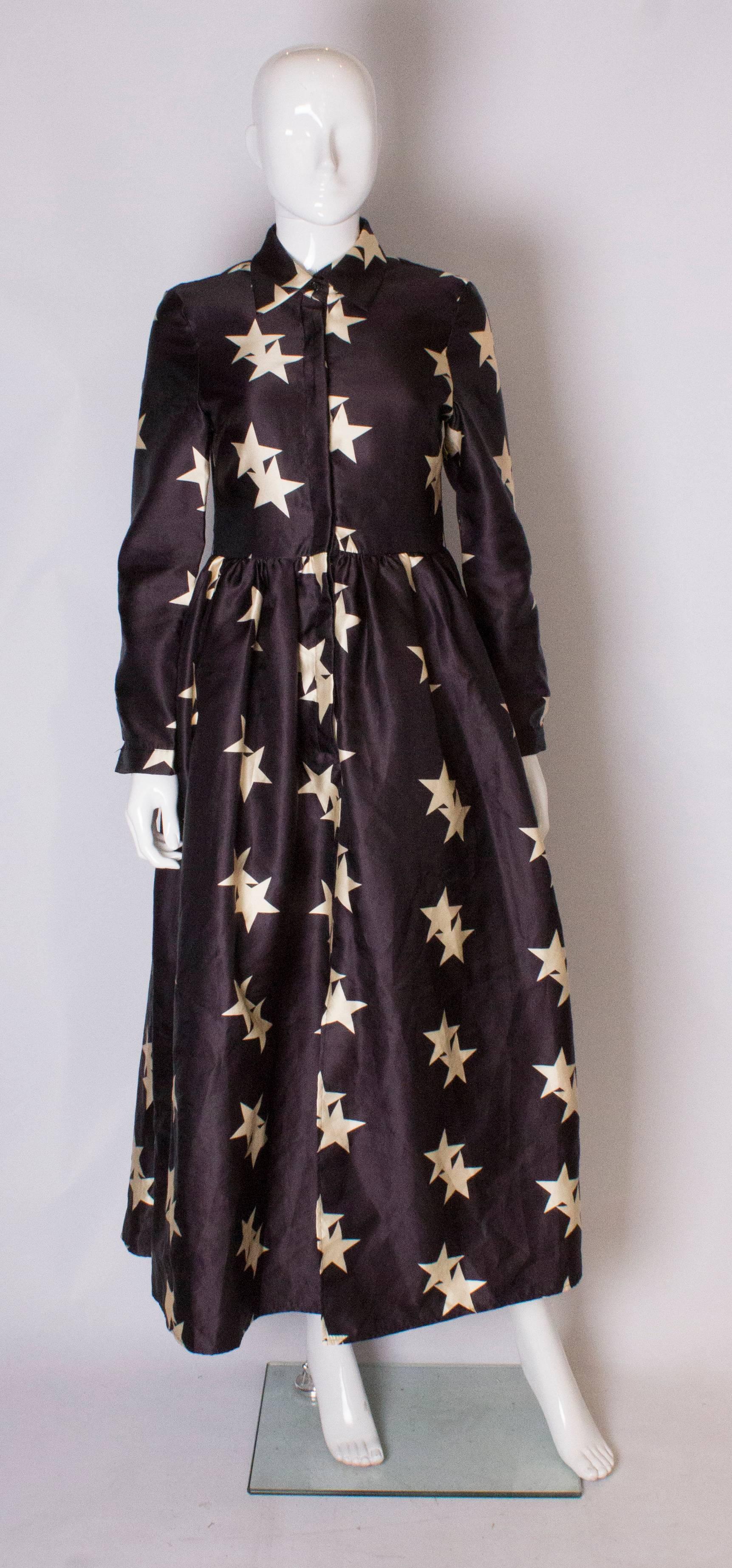A chic and easy to wear shirt dress in a wonderful star print.
The dress is in a deep mauve/blue colour with a star print. It has gathering at the waist and a button through front.