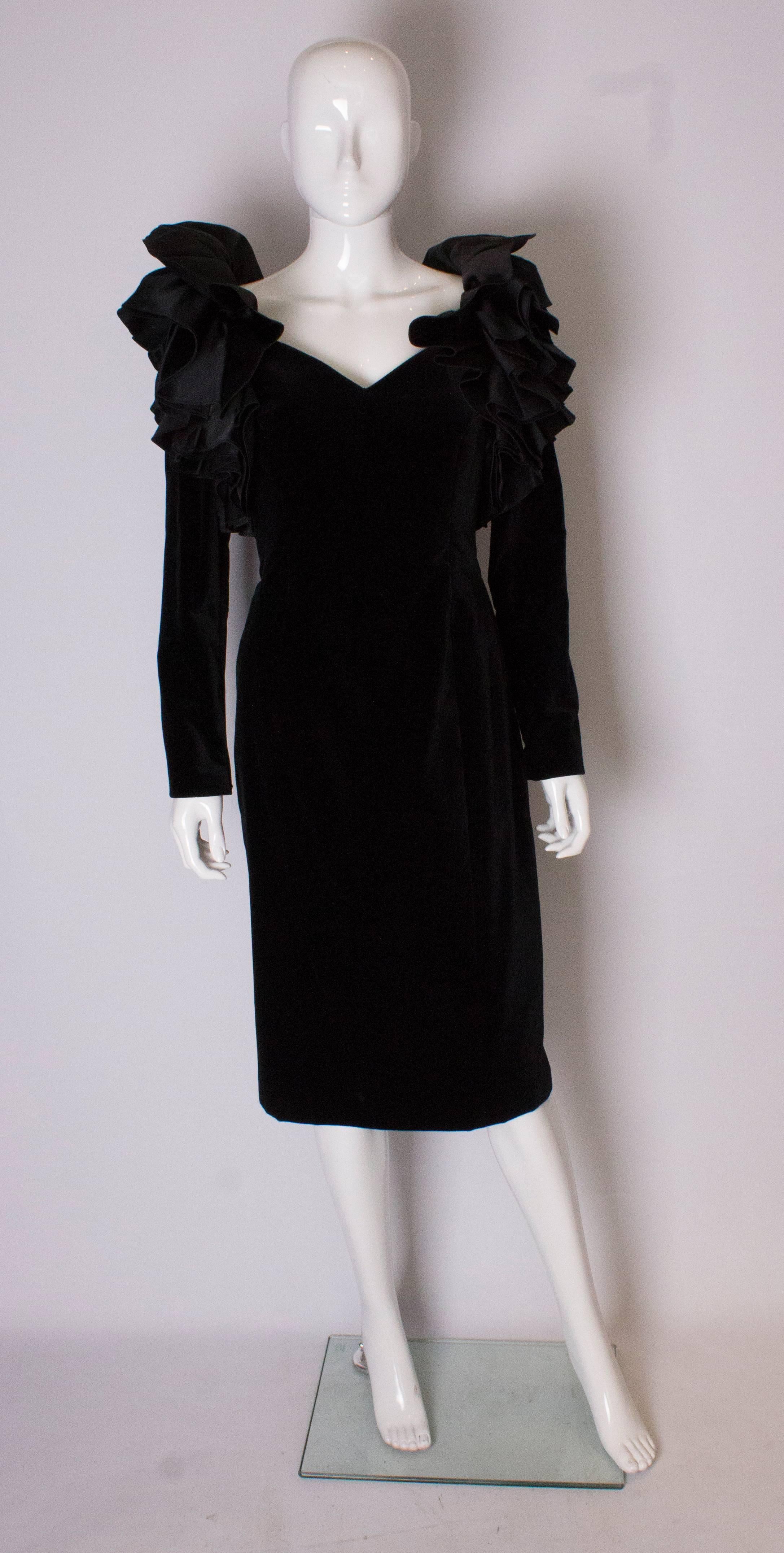 A great 1980s party dress by Gina Fratini. The dress has a v neckline, and long sleaves in black velvet.  It has wonderful frills on the shoulder and a central back zip.