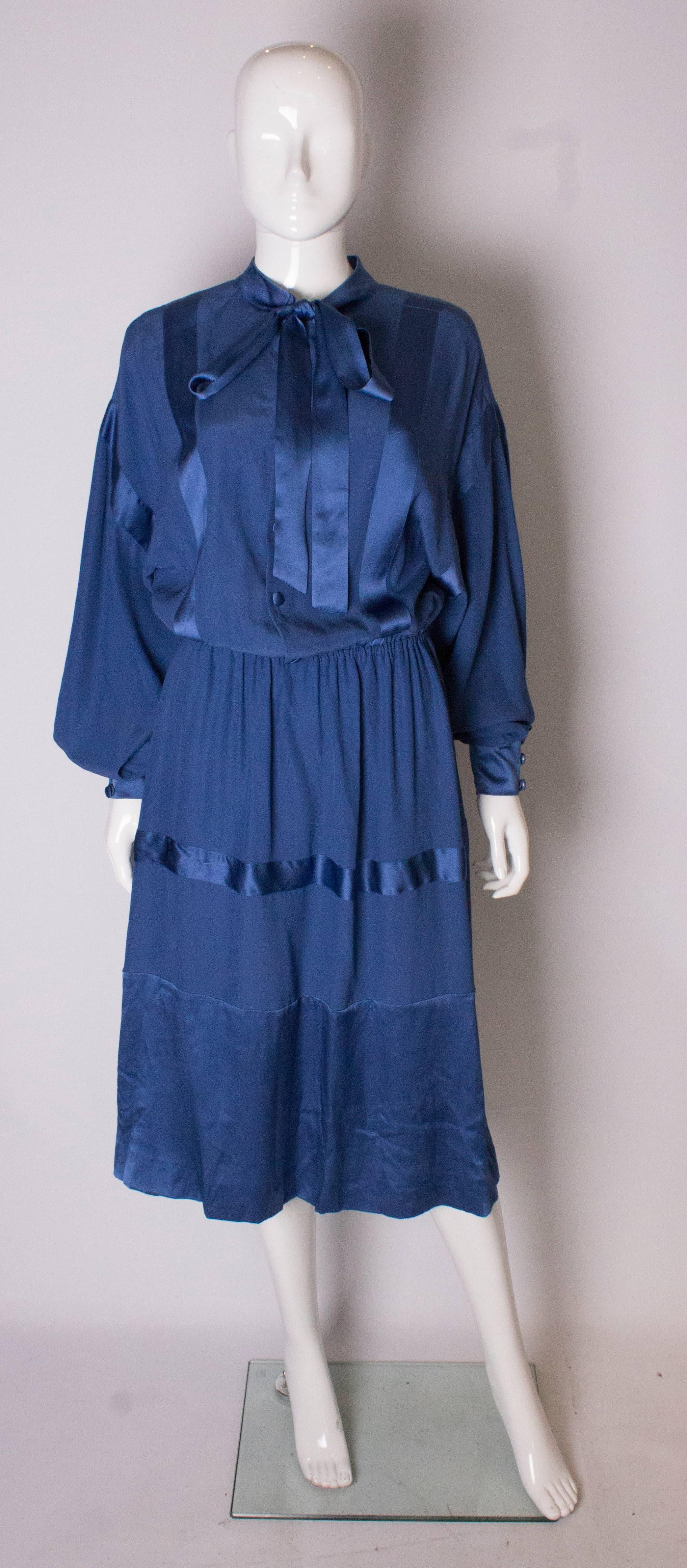 A chic  blue silk dress by Stefano Ricci for Herbie Frogg . The dress is in a blue silk with satin /ribbon panels . It  has an elastic waist, button front and tie neck.