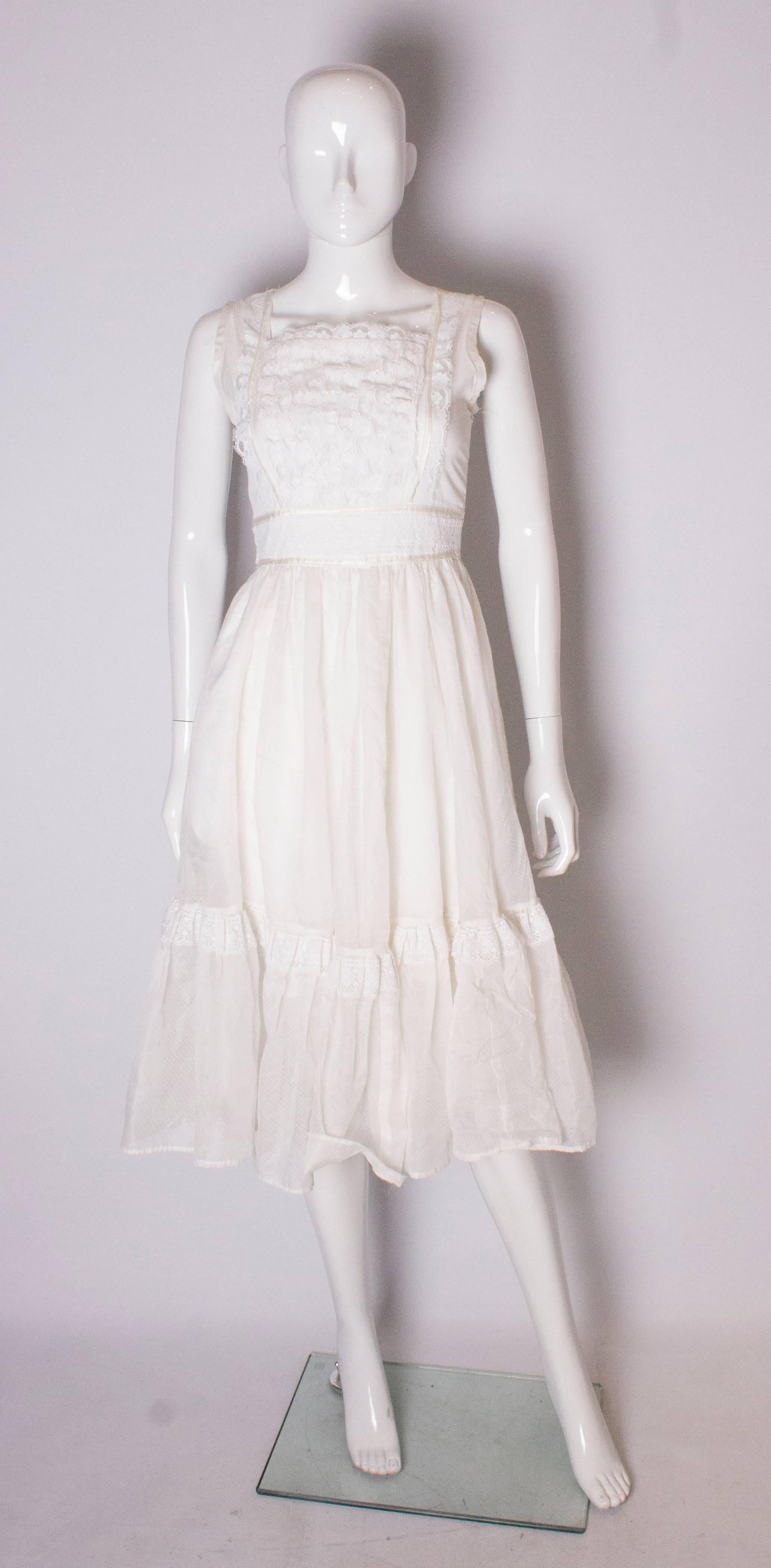 A pretty dress for Spring/Summer, in a white spot fabric, with lace detail on the front and above the frill. The dress has a square neckline, is lined and has a cental back zip.