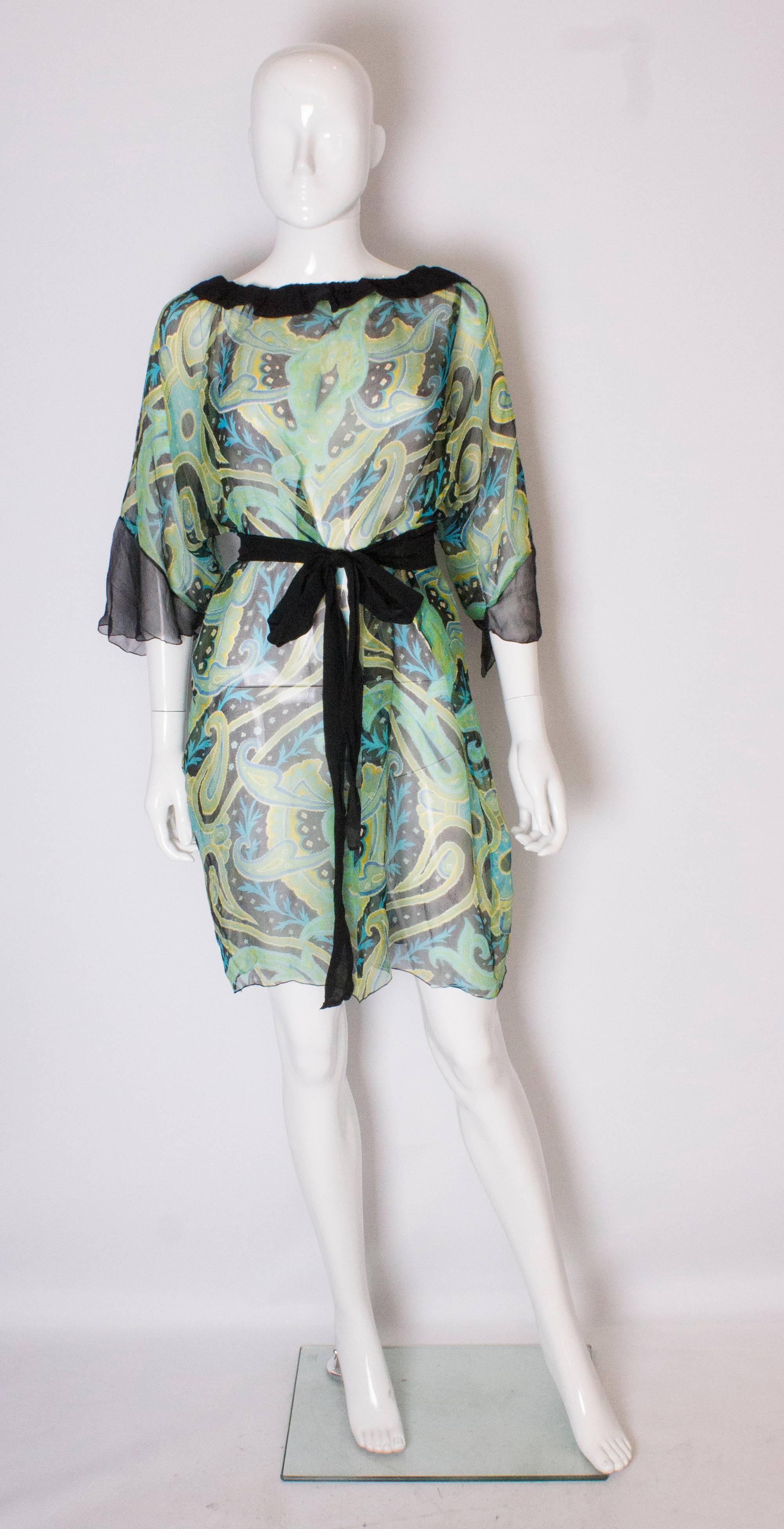 Ein schönes Seidenkleid für den Sommer in einer Mischung aus Grün, Schwarz, Blau und Gelb. Das Kleid hat einen schwarzen Seidenkragen, Manschetten und einen selbstgebundenen Gürtel.