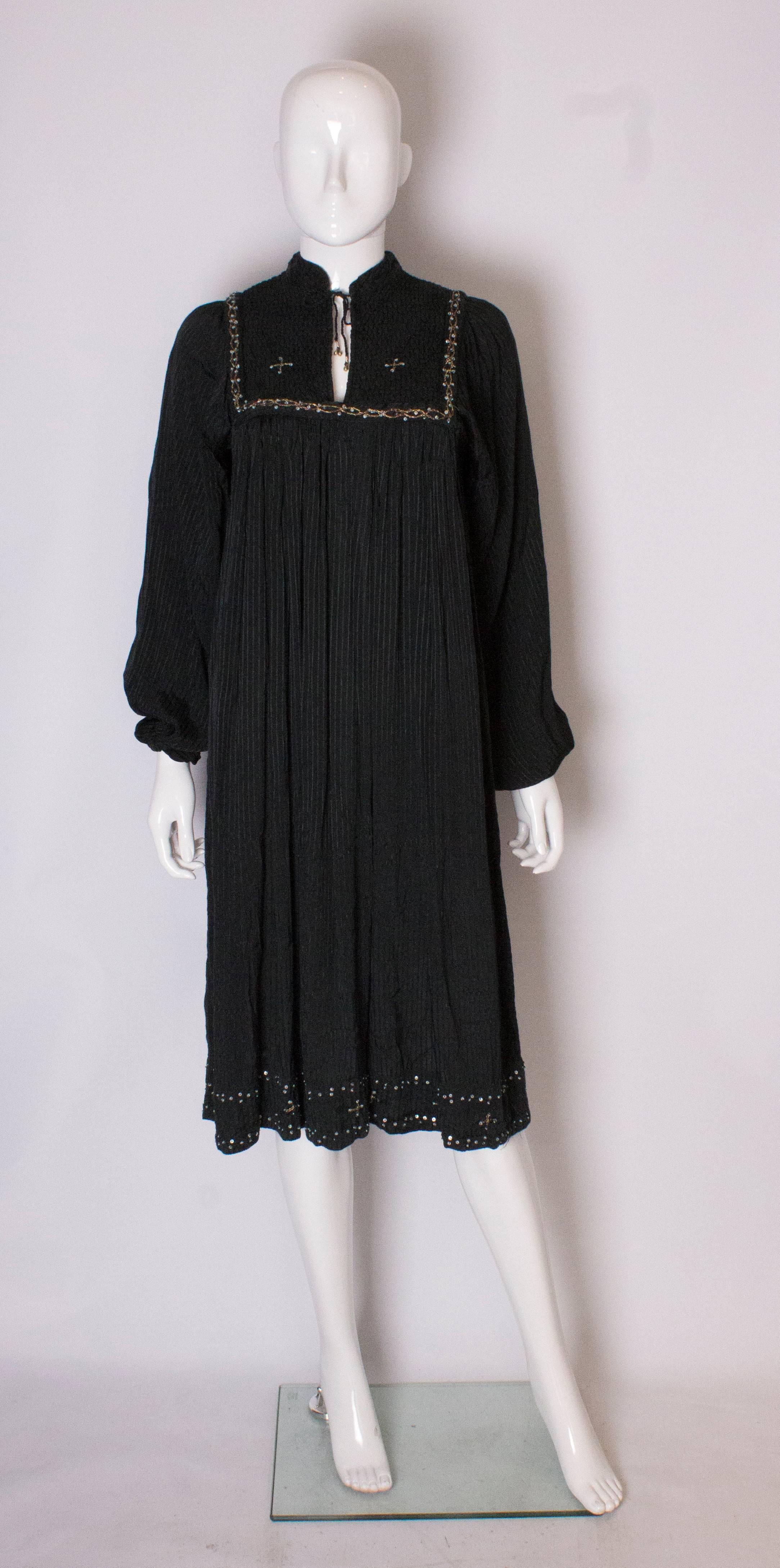 Un vintage chic et facile à porter  robe d'été. La robe est faite d'un tissu noir à rayures, avec des détails de matelassage sur la poitrine. Il est doté d'un lien à l'encolure et de poignets élastiques.