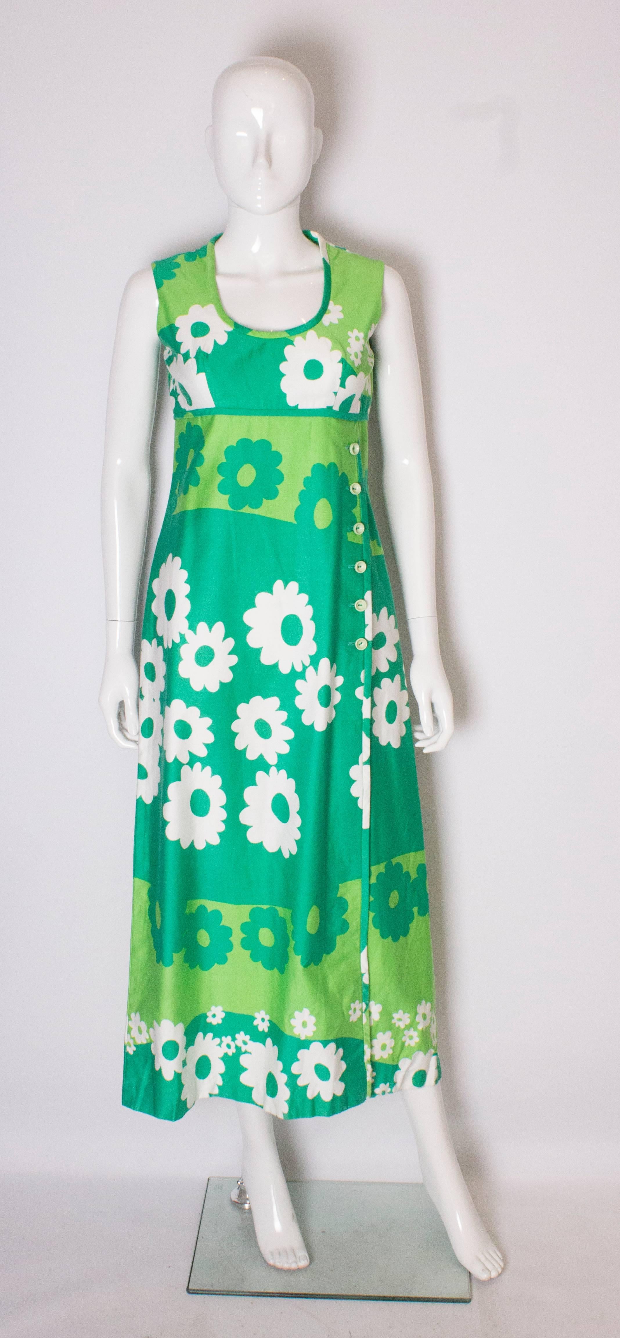 A stunning and bright 1960s  green floral printed dress, perfect for Summer. The dress is in a wonderful print and various shades of green and white. The  dress has a scoop neckline, central back zip, buttons down one side and a 29'' slit on one