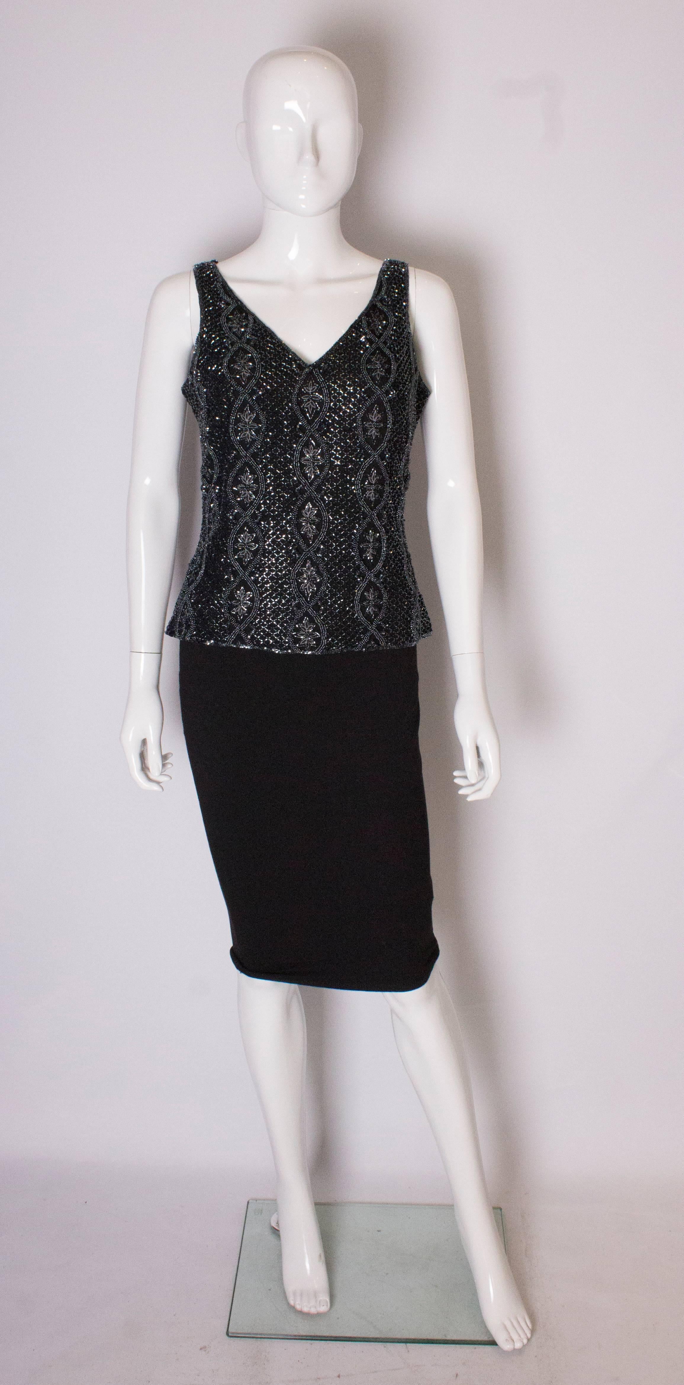 A chic evening top by Adrianna Papelle. The top has a v neckline front and back , with beading in a floral design and in vertical columns.  it has  a central back zip.