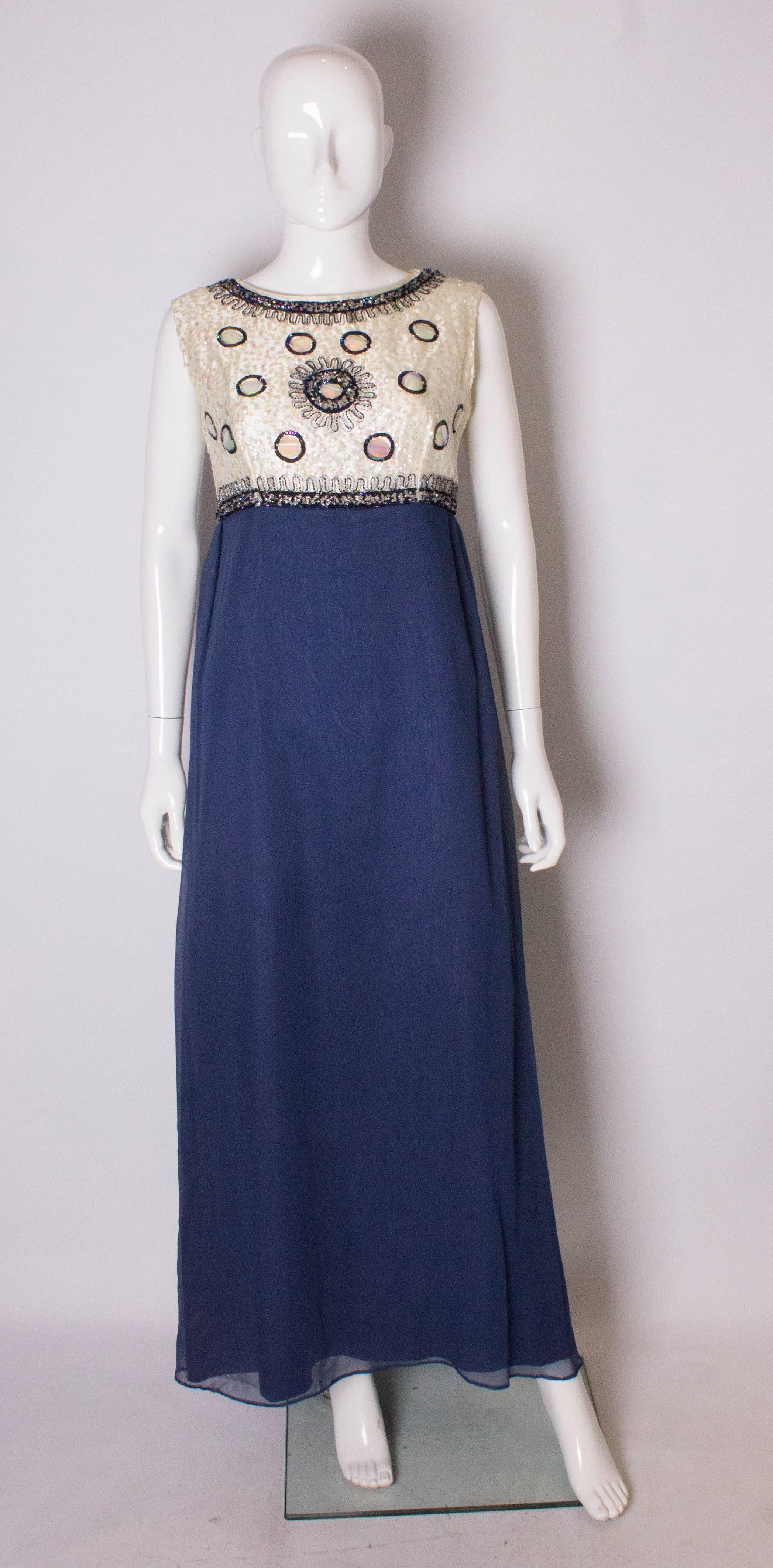 A chic evening gown by British designer  Laura Phillips. The upper part is covered in a white  sequin background embellished with blue beads and sequins.  The skirt is a blue chiffon like fabric. The dress has a central back zip and is fully lined.