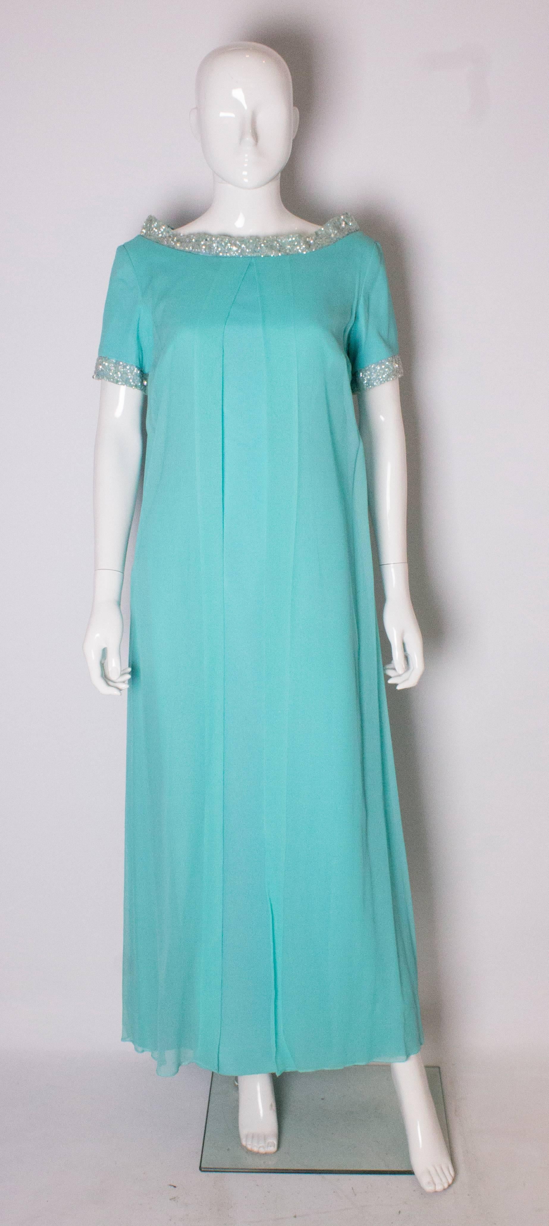 A wonderful vintage gown by Polmarks Model.  The gown has an attractive neckline with bead and sequin embellishment . The embellishment is also at the end of the sleave.The gown is column style wth a chiffon over layer.