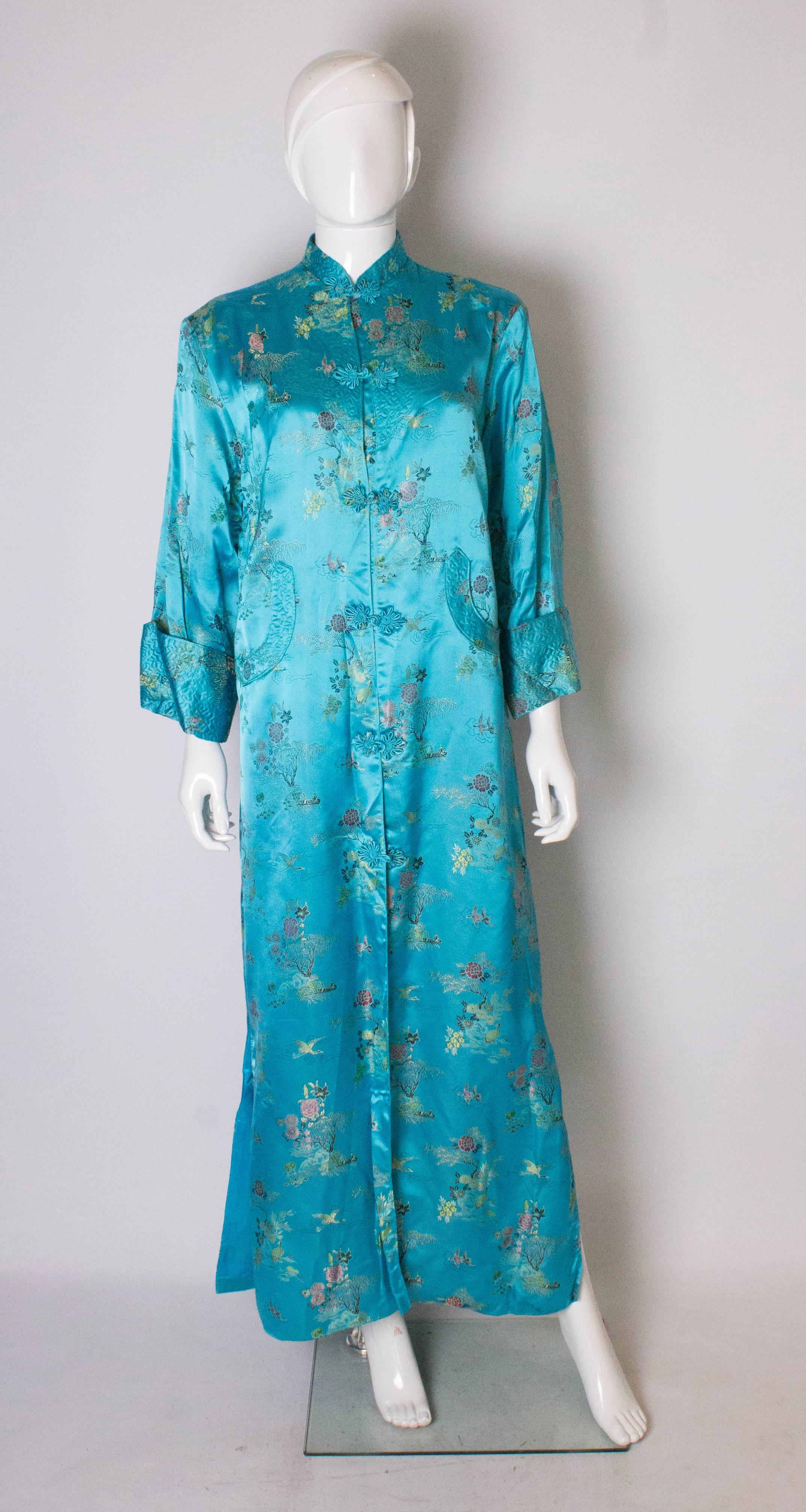 A stunning long  turquoise satin chinease coat . The coat is fully lined, has a stand up collar and  two attractive pockets at the front.  It has 17'' slits on either side, and elbow length sleaves.