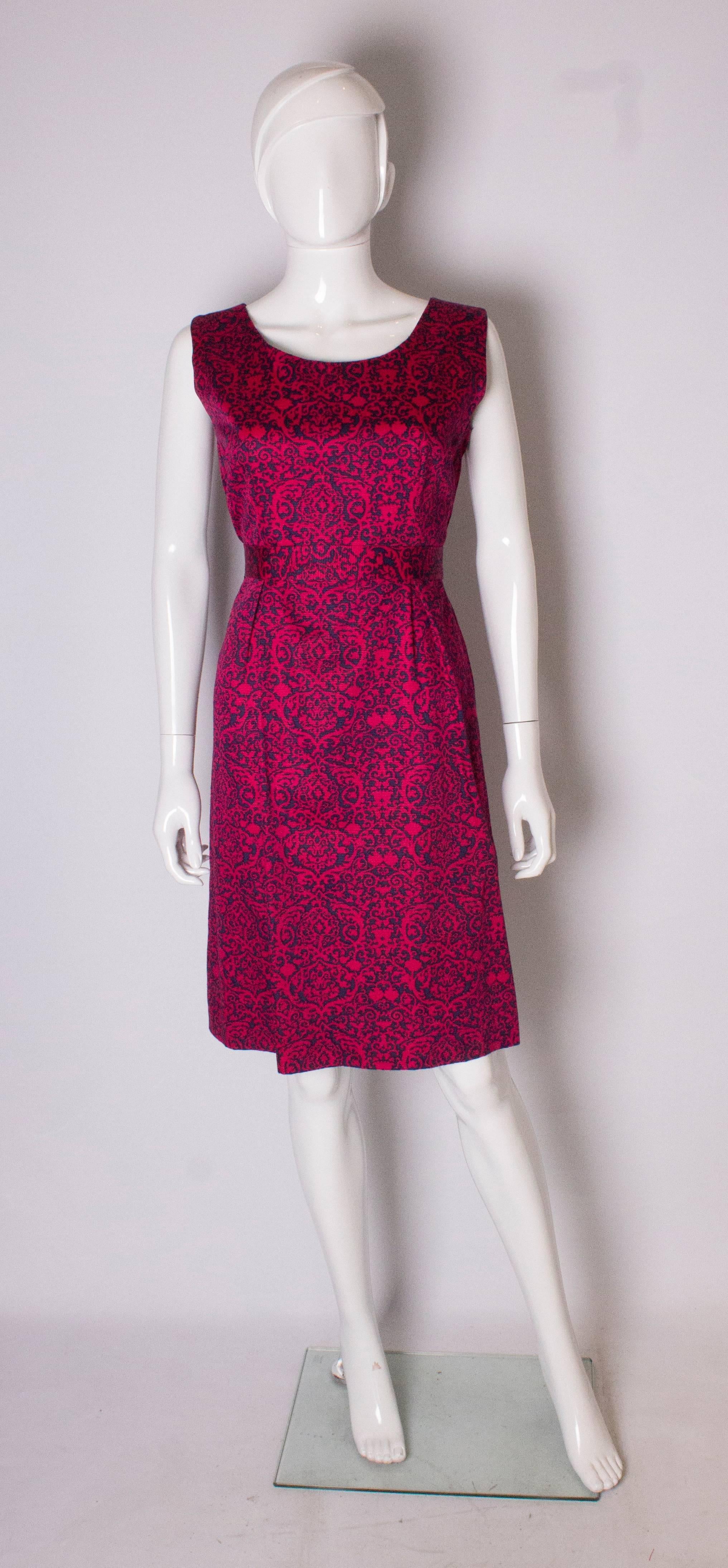 Un chic  Vestido de Cresta Couture. Fácil de llevar  El vestido es de tela azul marino y rosa, con un cinturón de tela propia. El vestido tiene dos pliegues en la parte delantera  y una abertura lateral con cremallera.