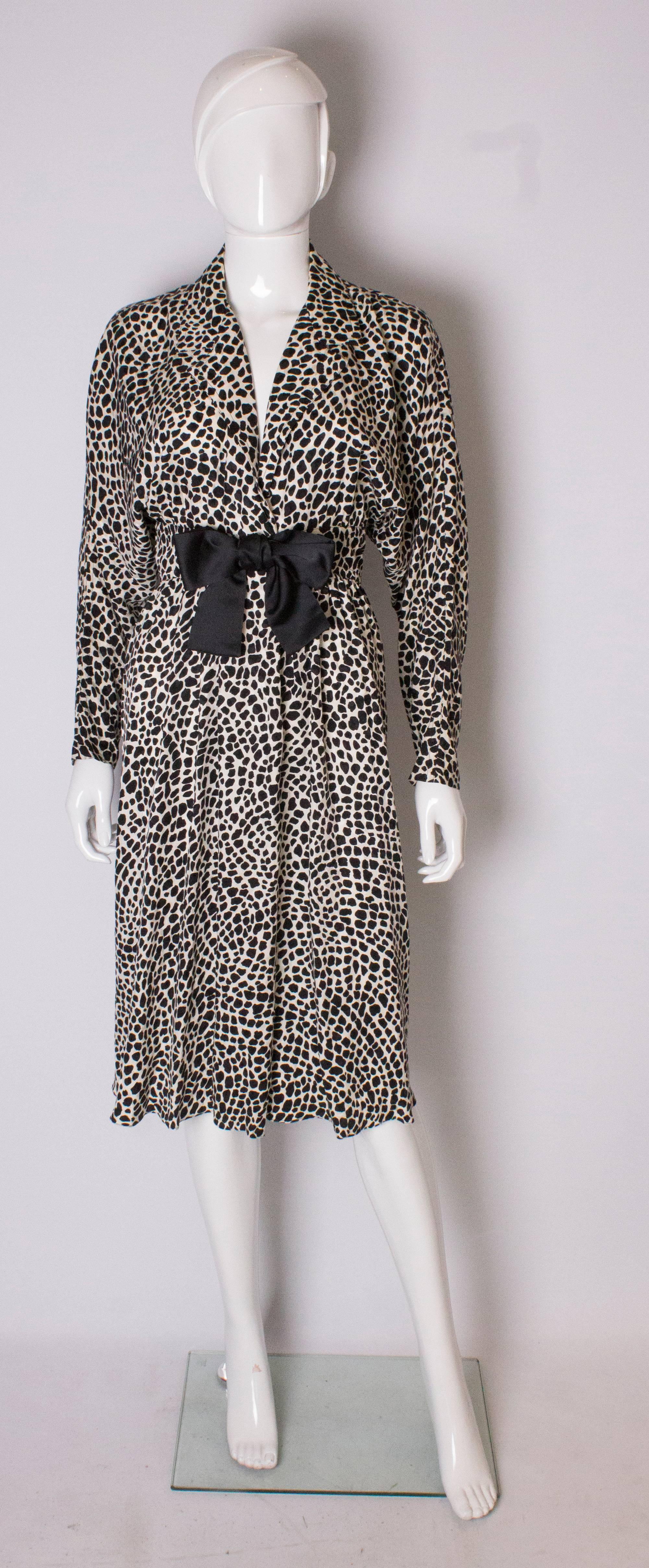 A chic black and white dress by American designer, Adele Simpson. The dress is in a wonderful black and white print fabric, and  has a v neckline, with wide collar and bow detail at waist leval.It has front popper opening below waist leval.