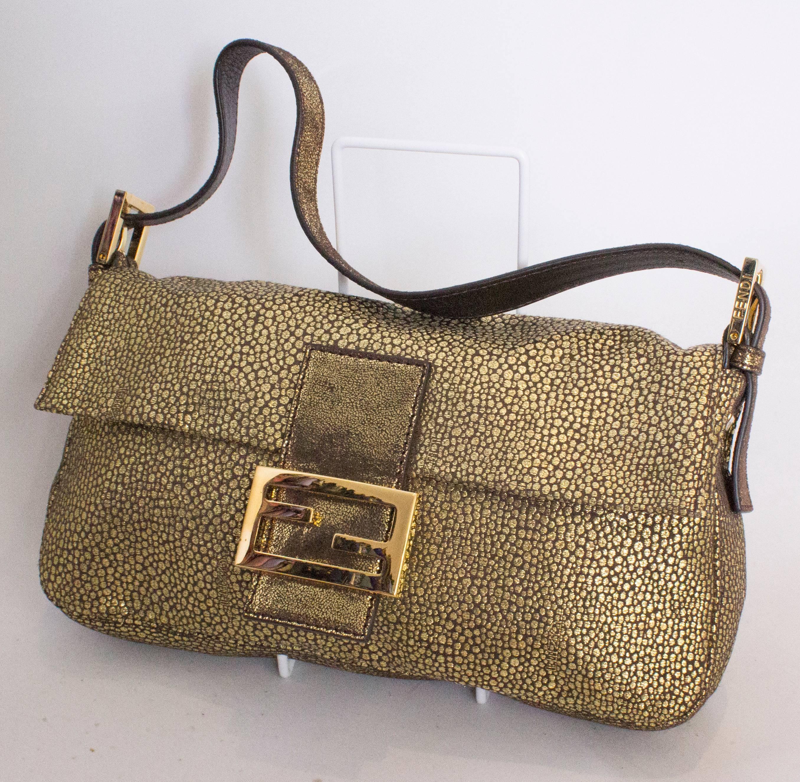 Eine schicke Tasche der italienischen Firma Fendi. Die Tasche ist im Baguette-Design aus einem goldfarbenen Stoff mit Animal-Print.  Es hat eine Klappe über der Vorderseite mit einem Druckknopfverschluss und einer großen Fendi-Schließe sowie eine