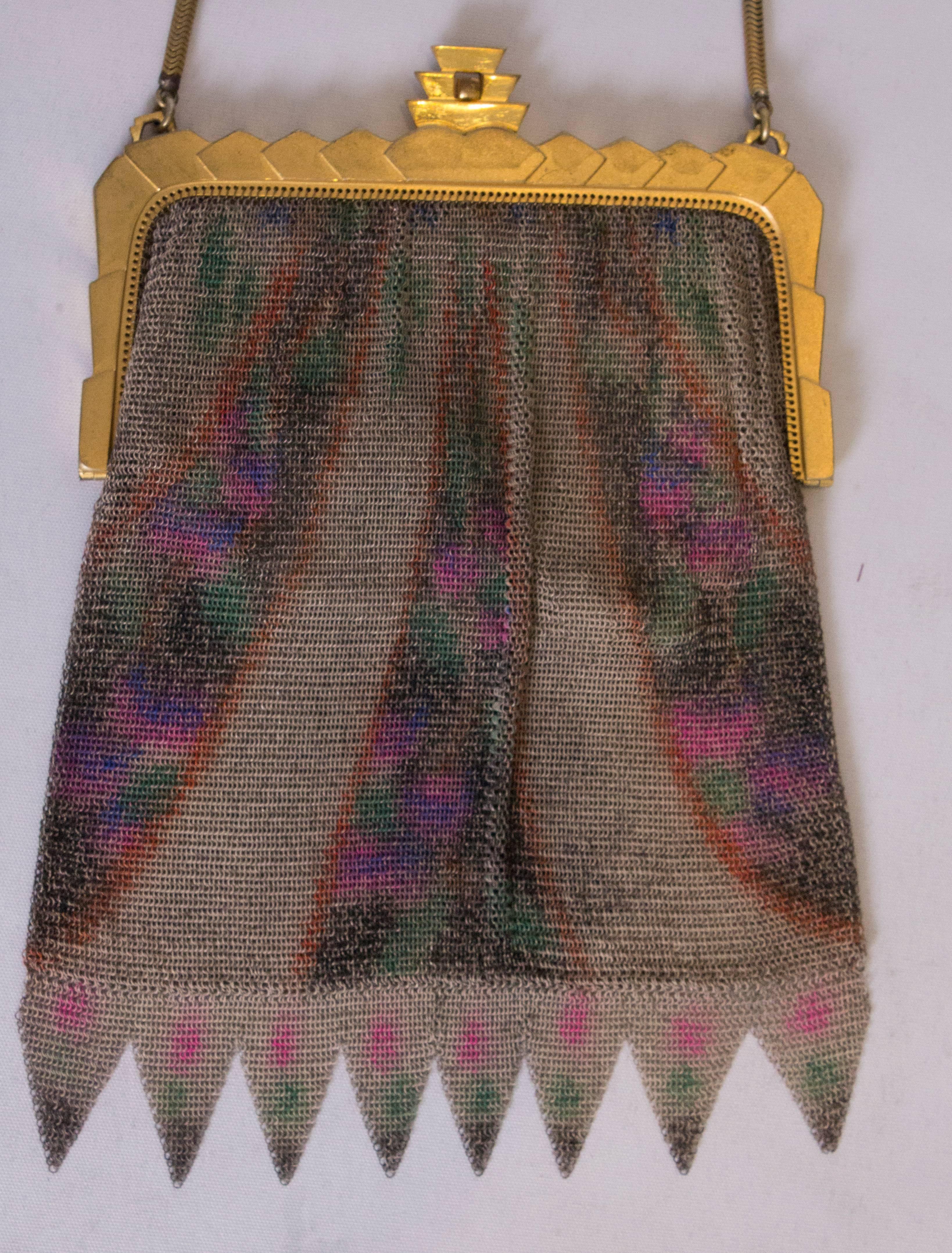 A pretty art deco bag by Whiting and Davis. The mesh bag  has a grey background with a multi coloured design in lilac , bue and red, with  fringing at the base. Internaly it is lined in satin with an internal pouch pocket. The pretty 'gold ' frame