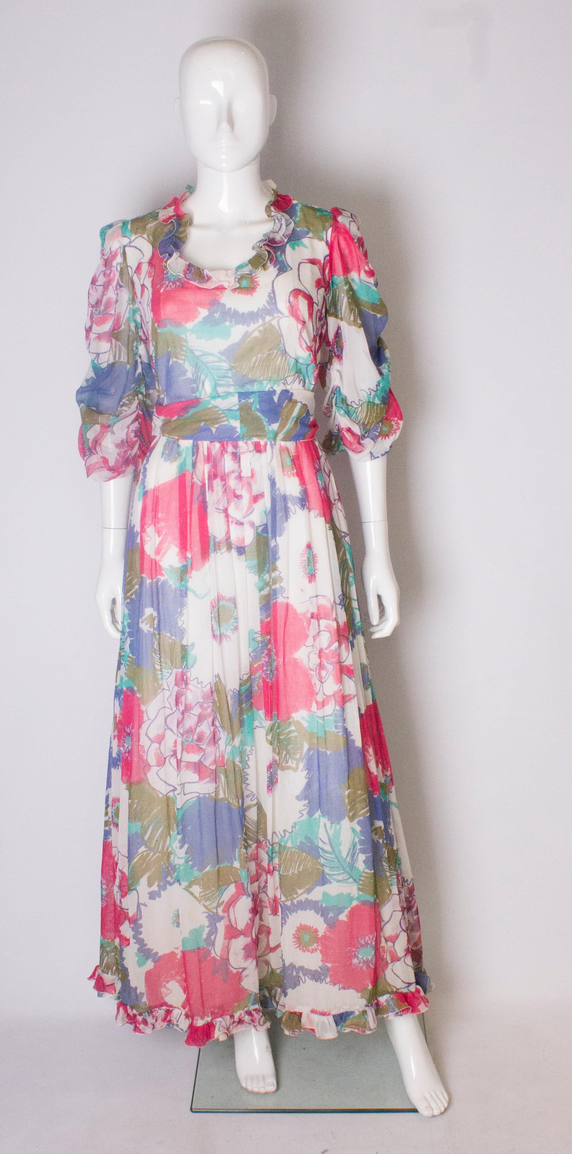A pretty floral  dress by British designer Donald Campbell. This dress is fully lined with a central back zip, and has a frill around the neckline and gathered sleaves. It appears to be hand painted on a cotton mix fabric, and has a self fabric belt.