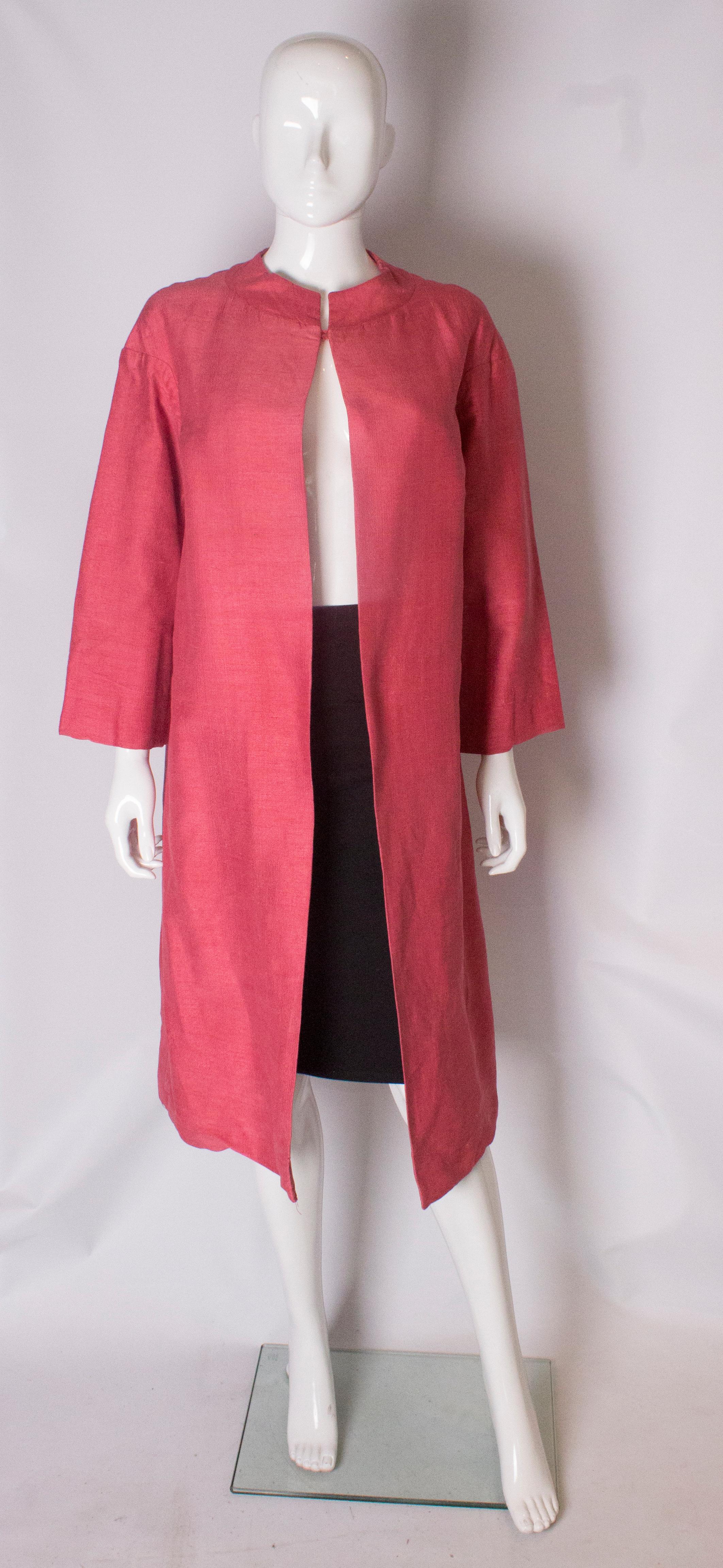  A pretty duster coat by Liberty of London. In a dusty pink raw silk, the coat has a mandarin style collar with hook and eye fastening, bracelet length sleaves  and is fully lined.