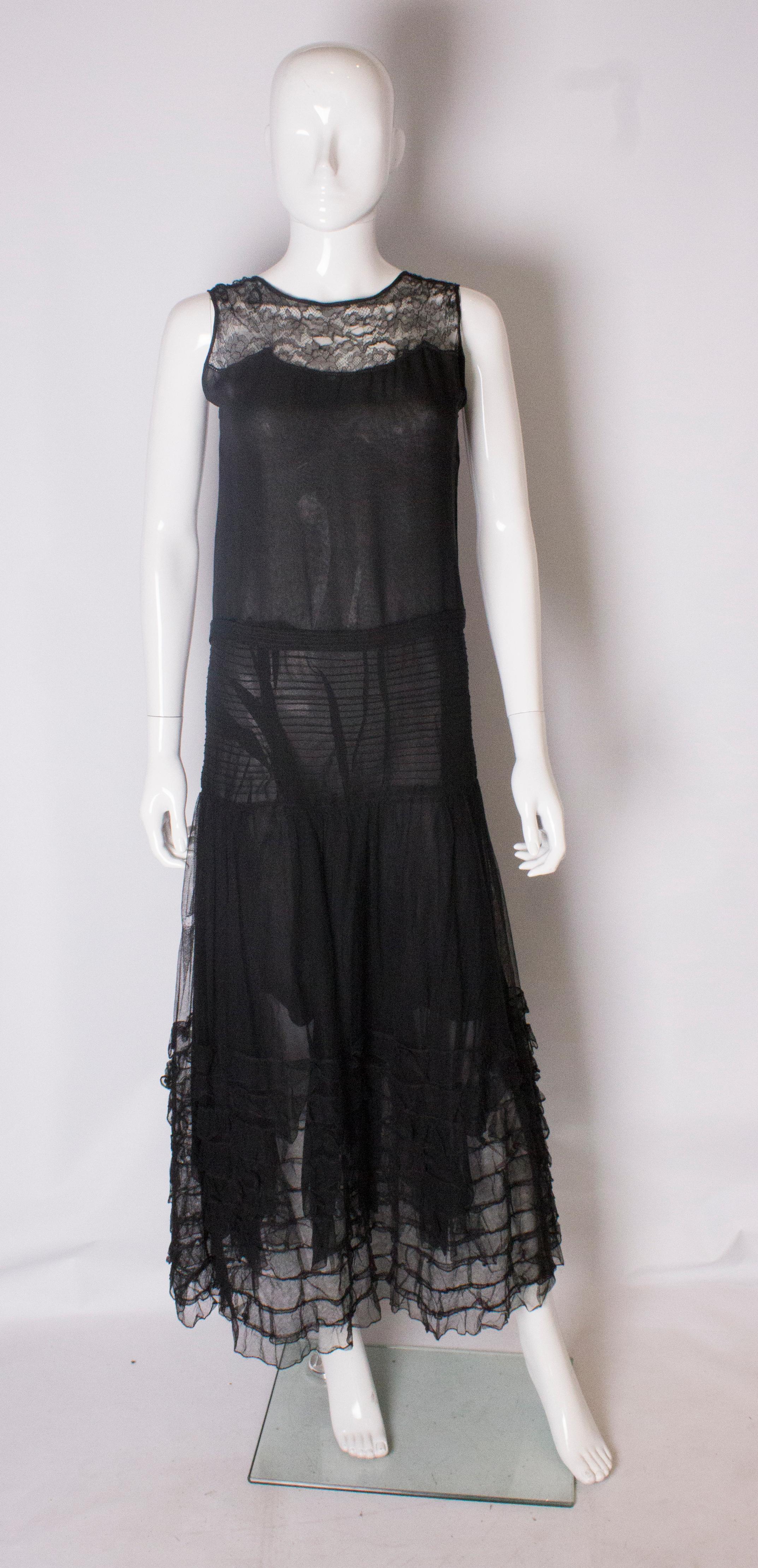 A pretty evening gown from the 1920s. The dress is sleaveless, with a lace bodice, horizontal ribbing at the hips and ruffles at the he. It is fully lined.