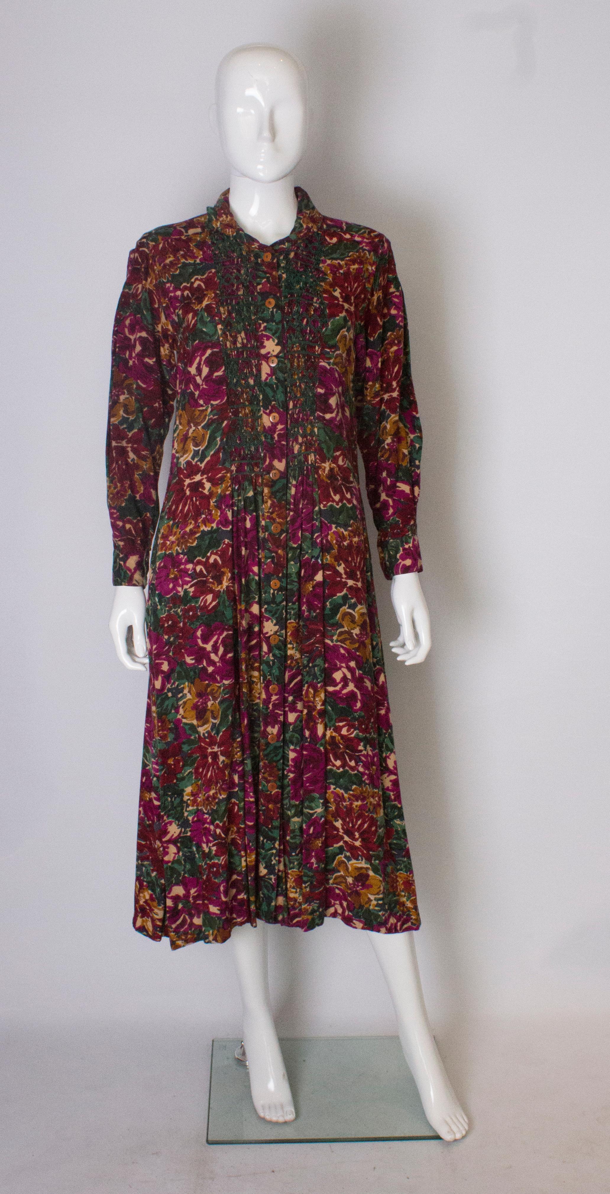 A great vintage dress by Monsoon.The dress is in a wonderful print of  burgundy, green ,brown and biscuit, and has wonderful green smocking detail on the front, back and sleeves. It has a button front opening,  an interesting shaped collar, and a