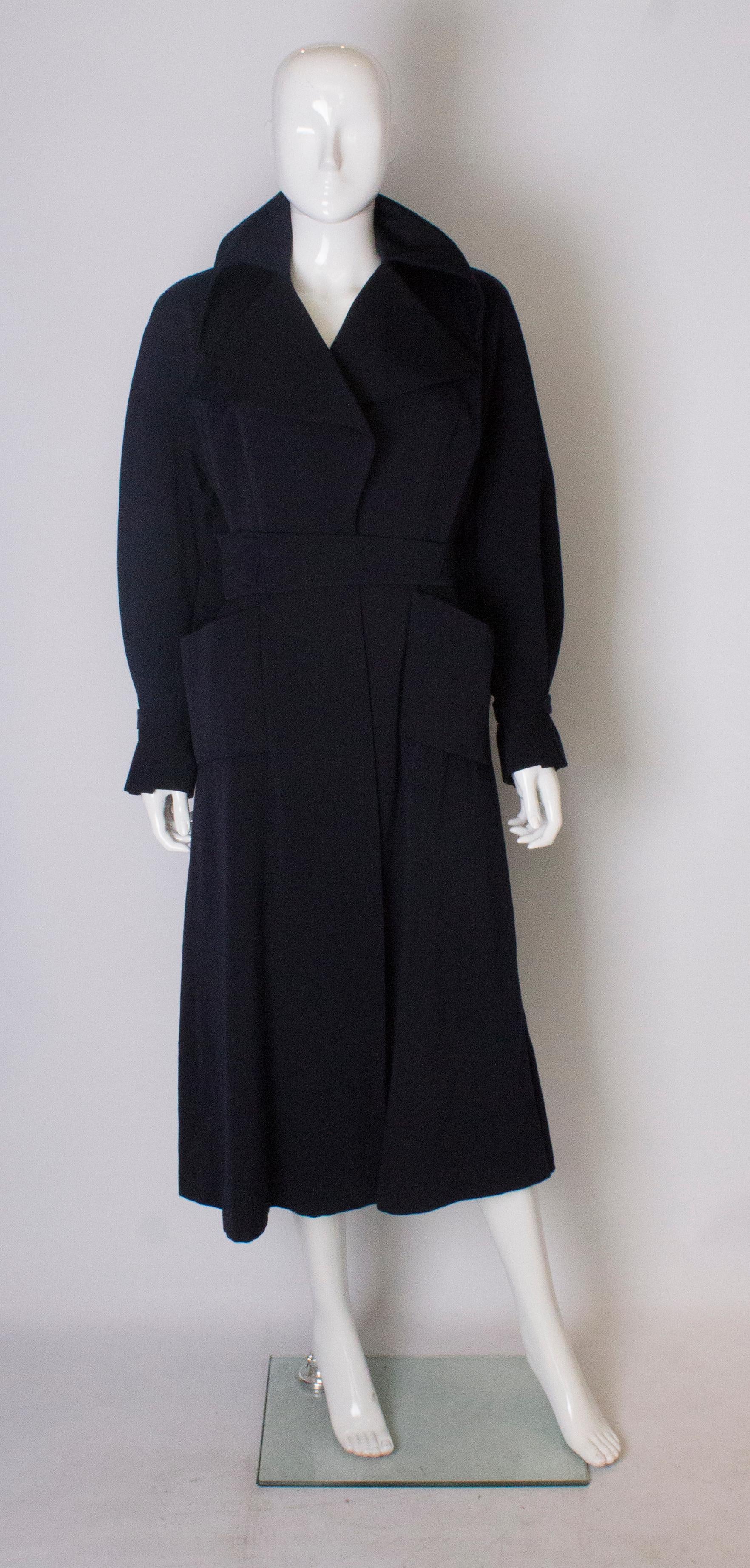 A stunning coat from the 1950s by Simon Massey.  In a wool fabric and fully lined, the coat has 2 pockets on the front, wonderful detail on the cuffs and  a self fabric tie belt. It is a wonderful design.