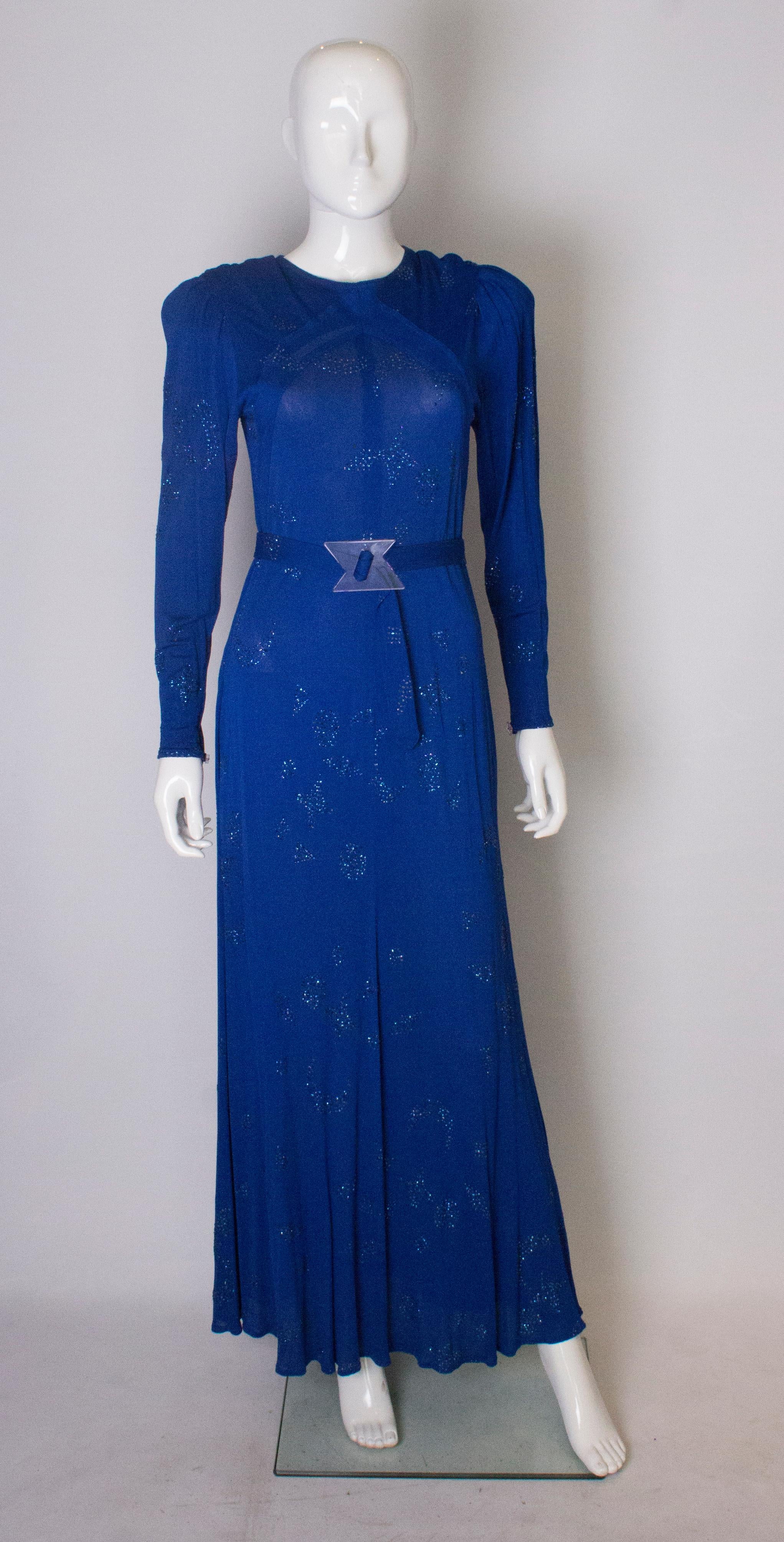 A chic statement dress from Jean Muir. The dress is in a stunning electric blue colour with a matching belt. with interesting buckle. It has a button opening at the back and is embellished all over with a stars and moon design.