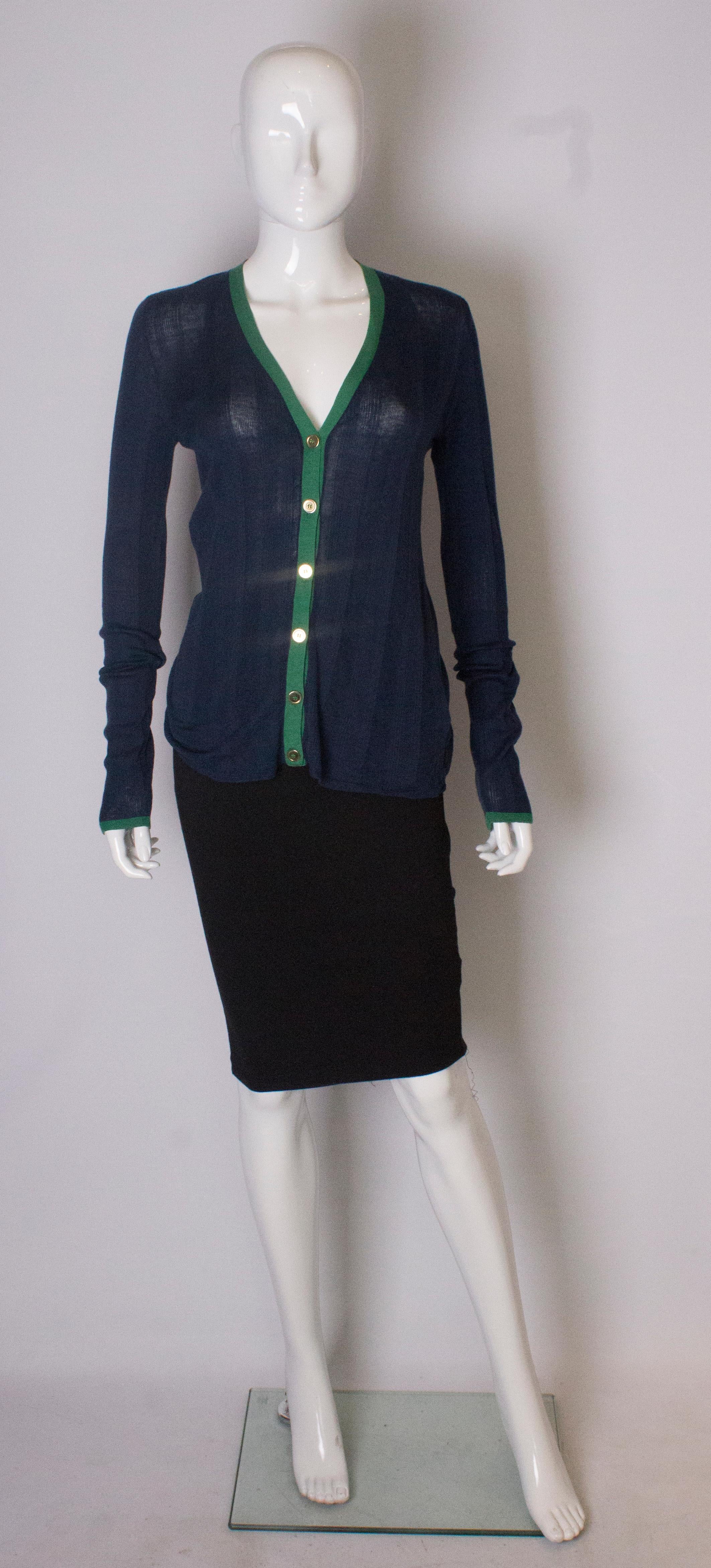 A chic and lightweight  by Yves Saint Laurent. The cardigan is 53% silk, 42% cotton, and 5% cashmere, and an ideal wieght for Summer .The cardigan is in a great shade of blue with green trim around the neckline and cuffs. It has a 6 button opening