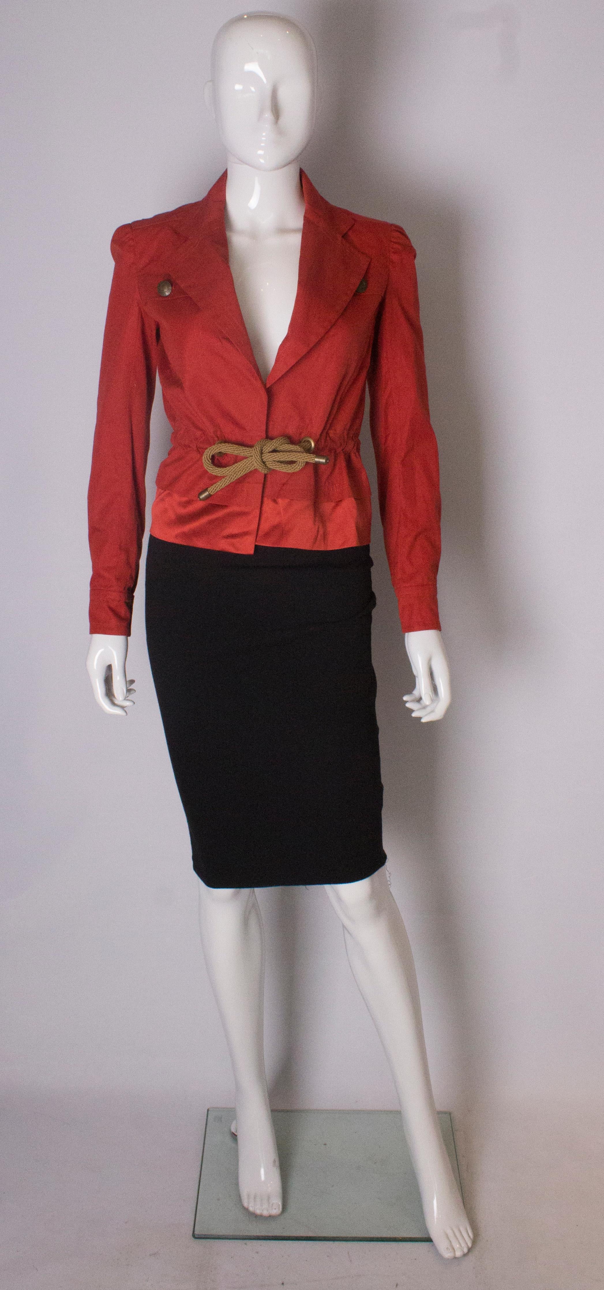 A chic vintage jacket from Yves Saint Laurent , Rive Gauche line. The jacket is in red cotton with an unusual rope drawstring waist, and silk like panel at the base. It has 2 breast pockets and single button cuffs.