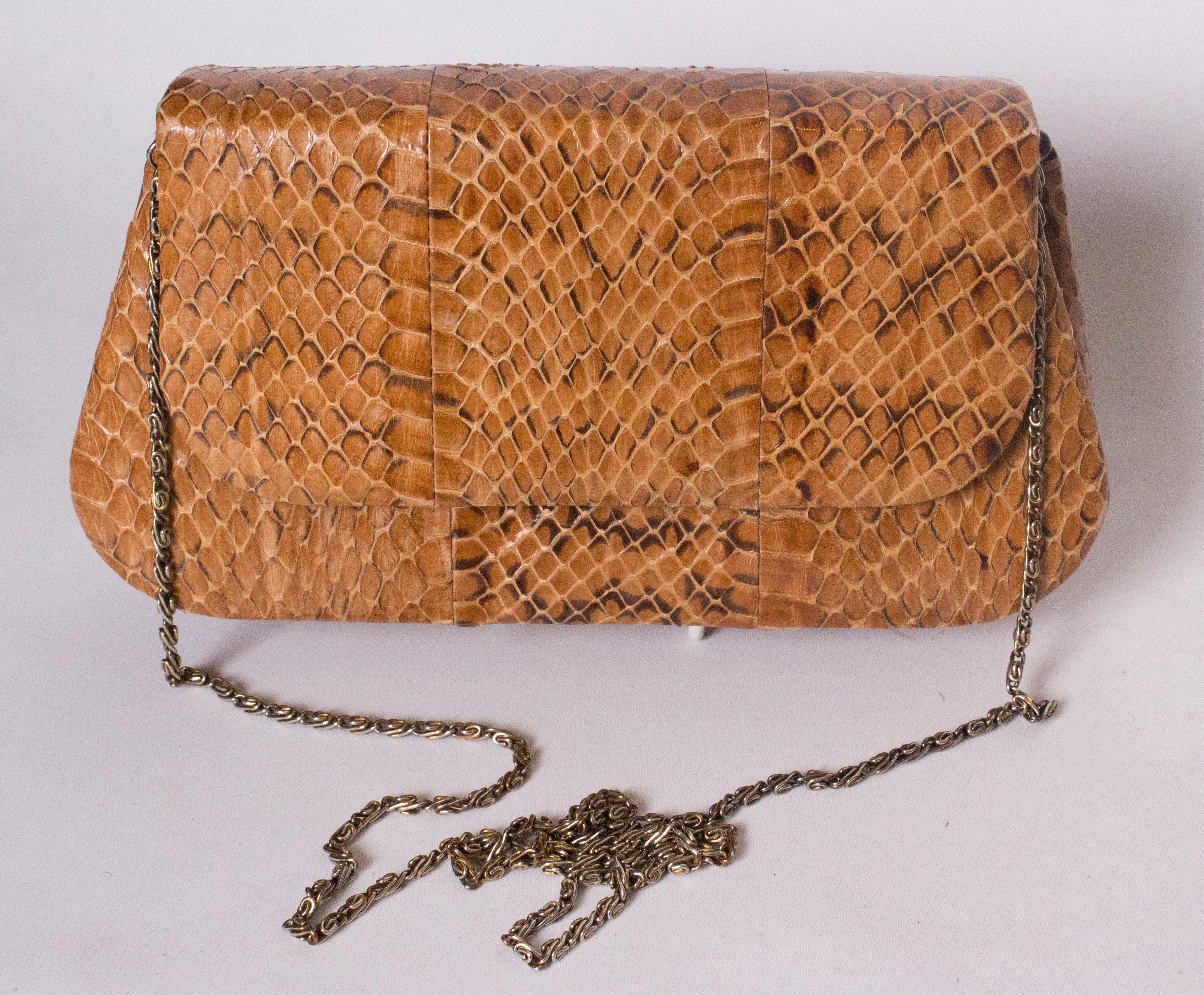 A chic snakeskin  bag in a nice mid brown colour. The bag has an internal chain and so can be used as a handbag, and a clutch bag. It has a fold over flap and one internal pouch pocket.
