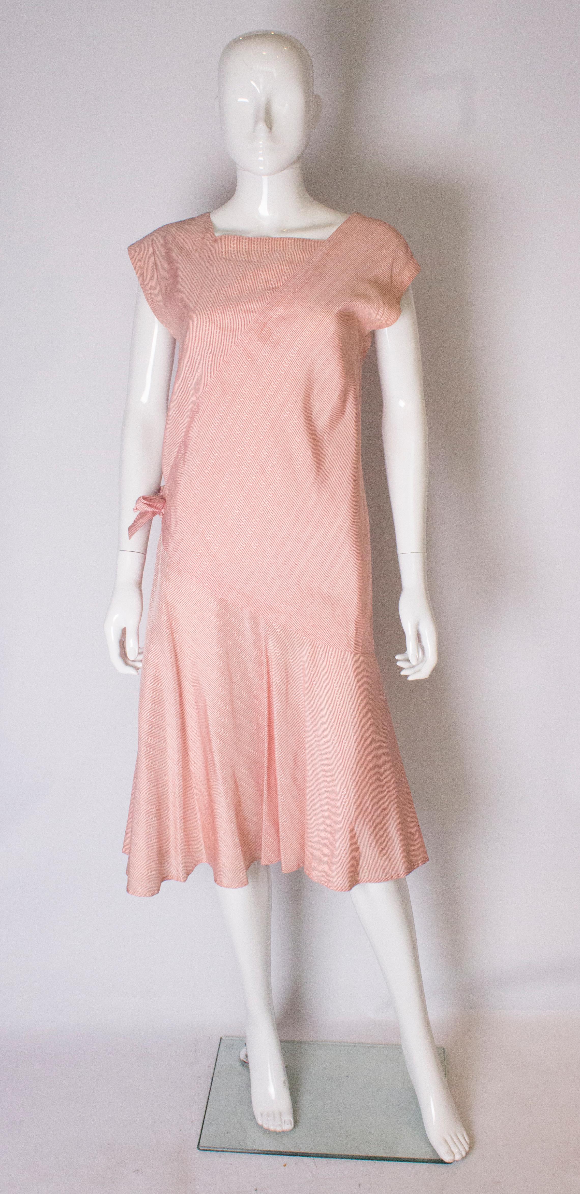 A vintage Benny Ong dress in a red and white stripe silk.
The dress is beautifully cut with a triangular detail on the front and back.   It has a self fabric tie at hip leval and the dress is fully lined.