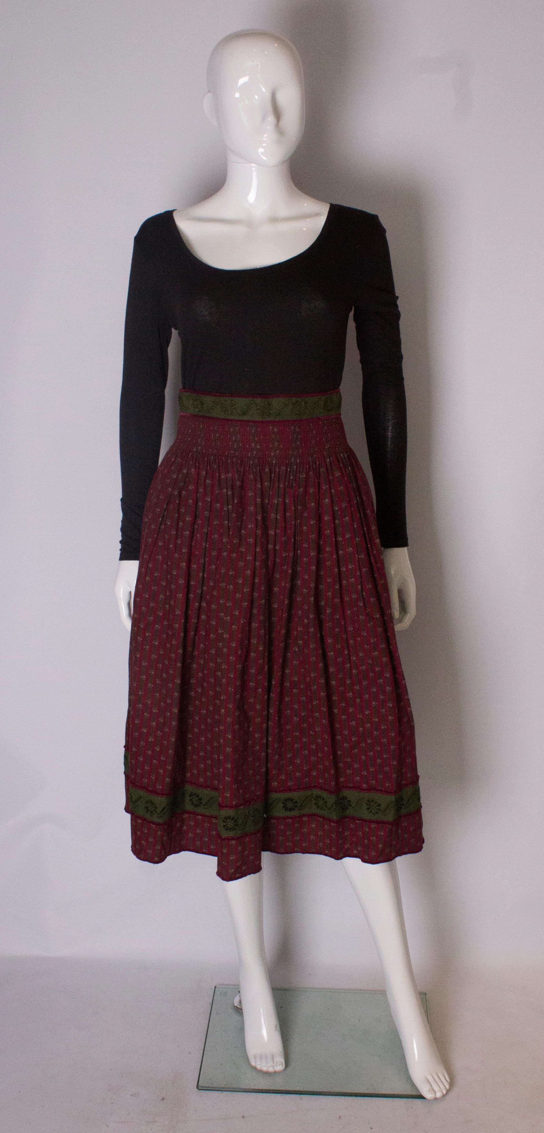 A great skirt for fall. The skirt has an olive waistband, and below this is 2'' of gathering, so the skirt doesnt bunch at the waist.
The fabric has a burgundy background with burgundy and brown vertical stripes. There is a row of braid near the