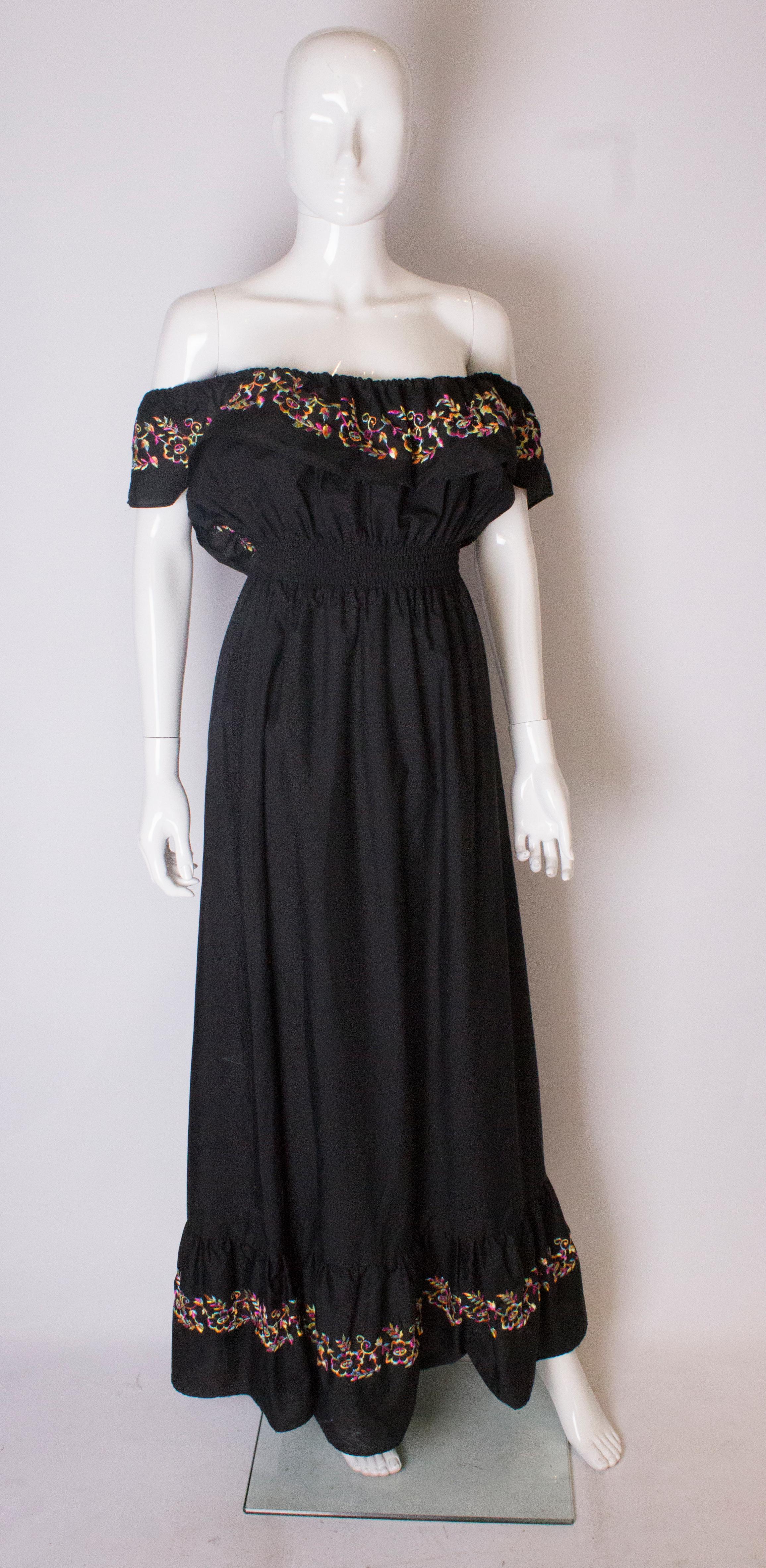 A pretty and easy to wear dress by  British firm Jinty. The dress is in black cotton , with an embroidered ruffle neck and  10'' frill at the hem. It has an elasticated waist and can stretch up to a 30'' waist.
