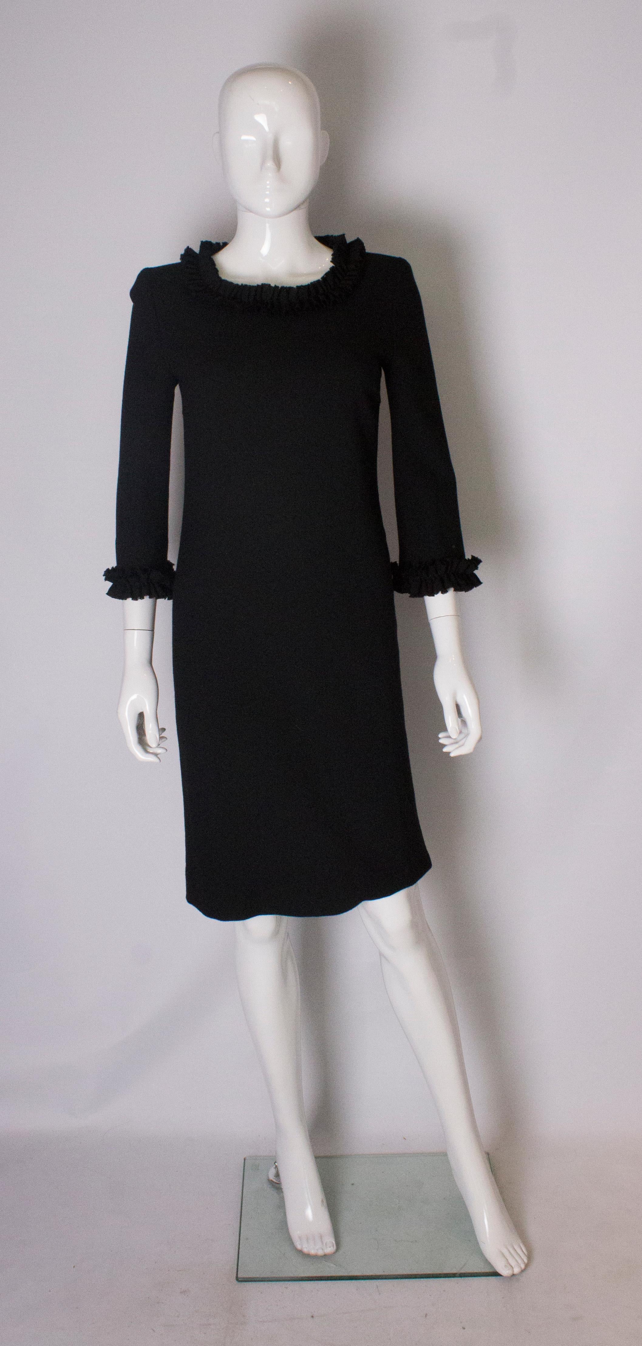 A simply stunning little black dress from Jean Muir ( main line). The dress  has a scoop neckline with frill trim , and elbow length sleaves with frill trim. It is in a black wool crepe and is fully lined with a central back zip.