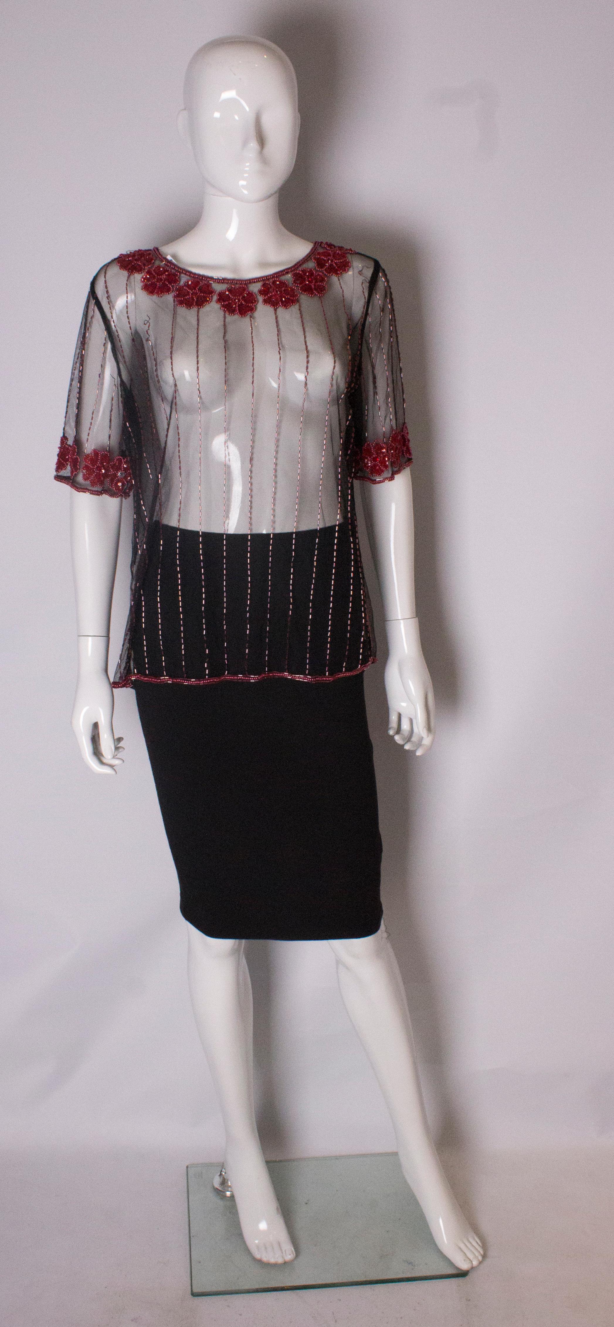 A  chic vintage evening T shirt  / top in excellent condition. The t shirt has a net background and pink and red sequin detail around the neck and end of sleaves . It has a popper opening at the back , and 3'' slit at either side .