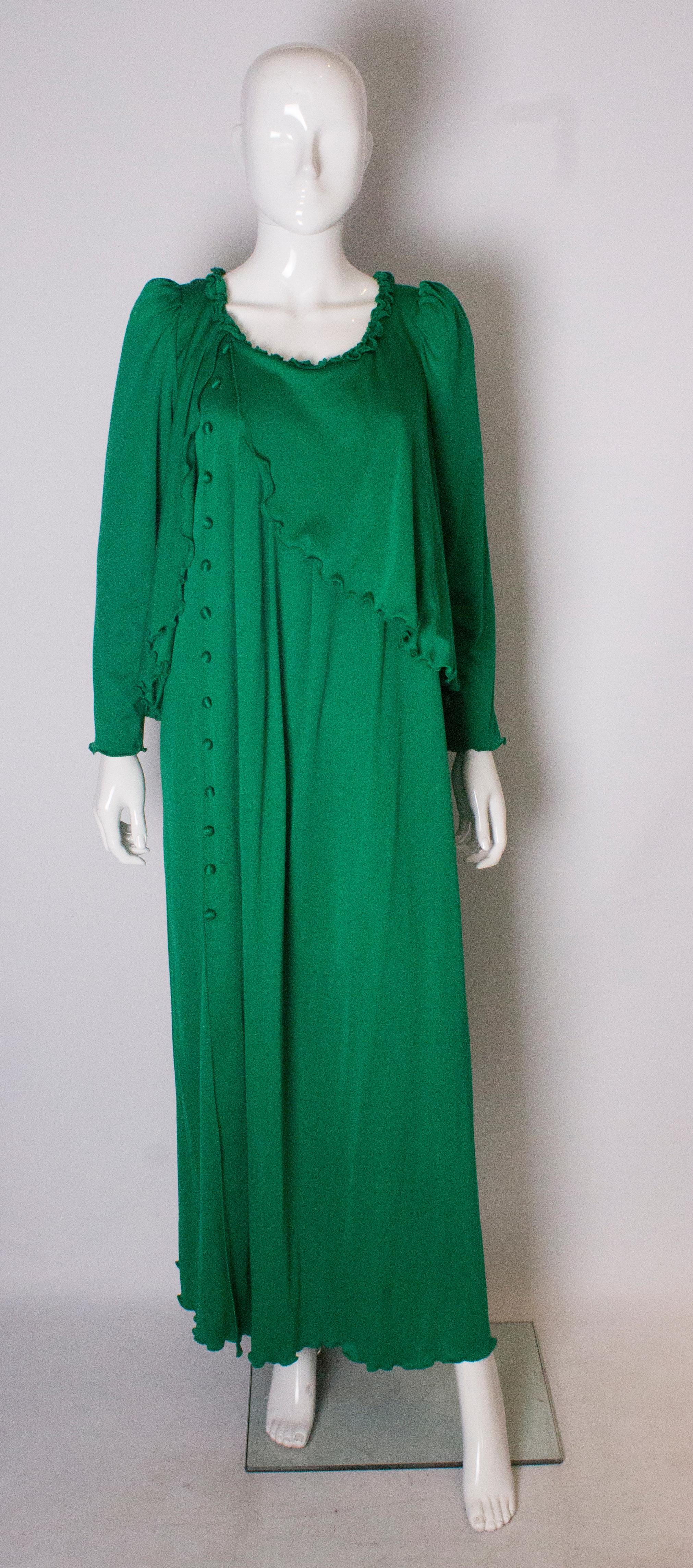 A great gown for Fall. In a vibrant green colour, this dress has elbow length sleeves with a frill edge, a fake capelet and 25'' slit at the front.
It has decorative buttons at the front and a central back zip.