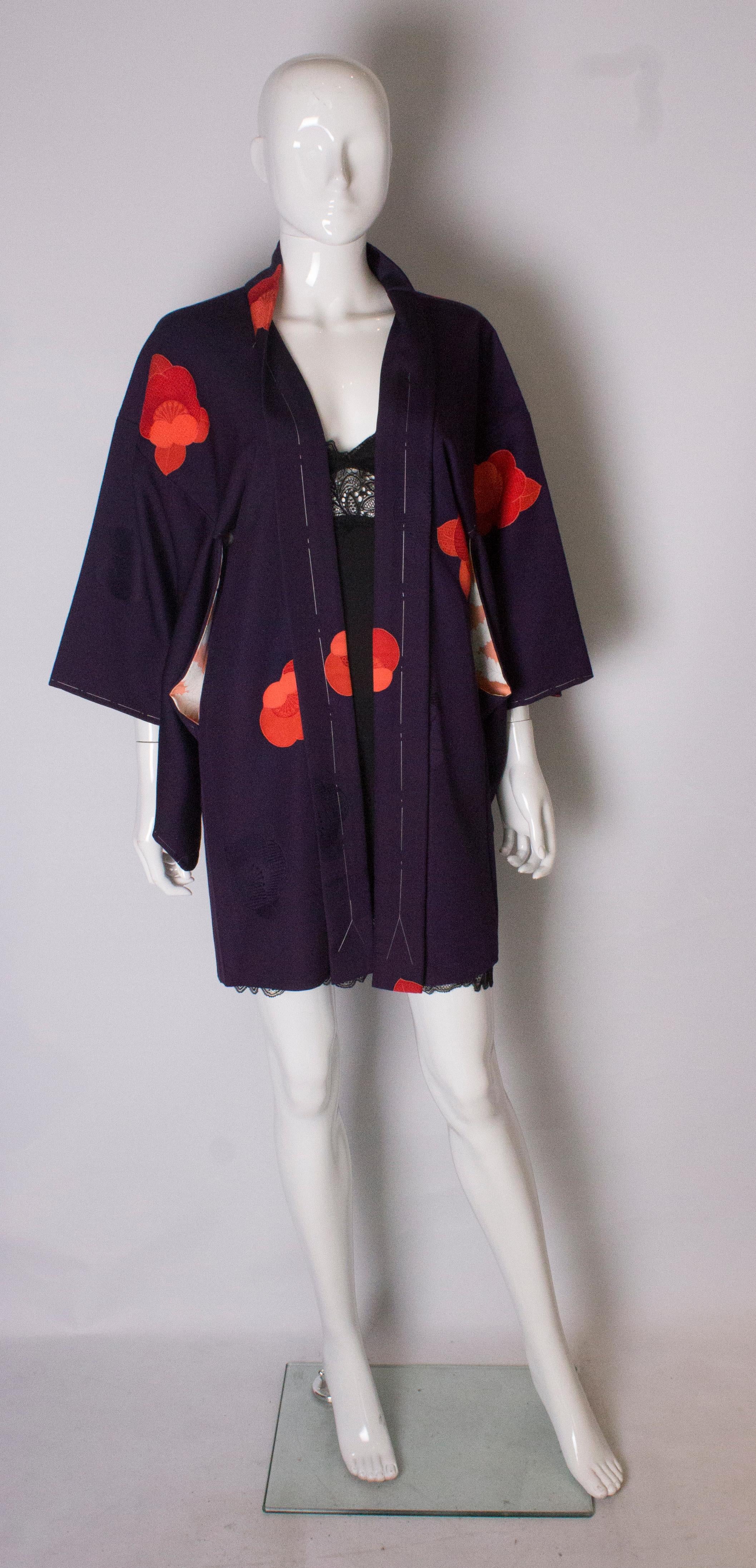 A chic short vintage kimono, that was  hand stitched in Kyoto in the 1980s. The fabric is purple decorated with purple flowers, and lined in a leaf print.