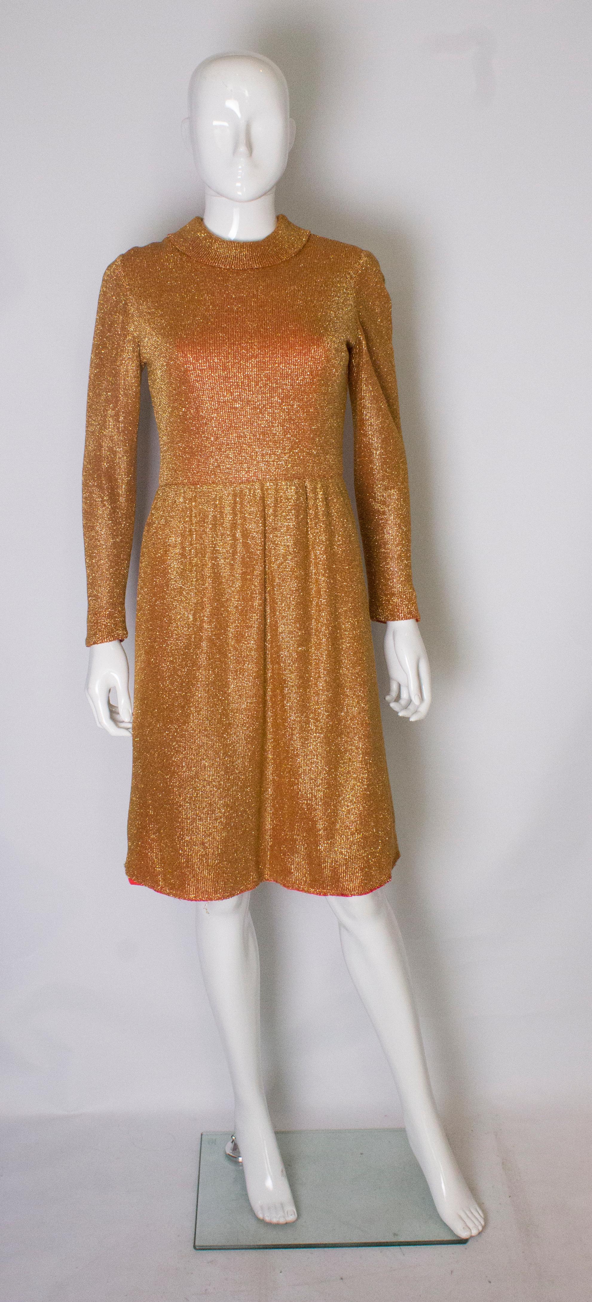 A real head turner , this dress is in a wonderful autumn/fall  gold colour, and lined in red. The dress  has a roll collar, gathering at the waist, a central back zip and ribbing at the cuffs.