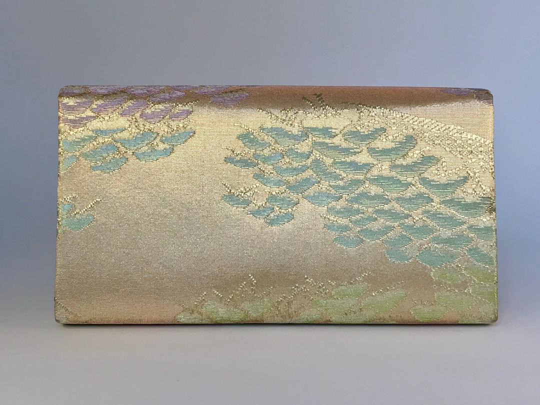 A pretty evening bag in a pink and gold silk fabric from an old obi belt. The bag has a flapover front with a popper fastening and one internal pouch pocket. It is decorated with a vintage crystal swan. Width 9 1/2'', height 5'',depth 1 1/2 ''