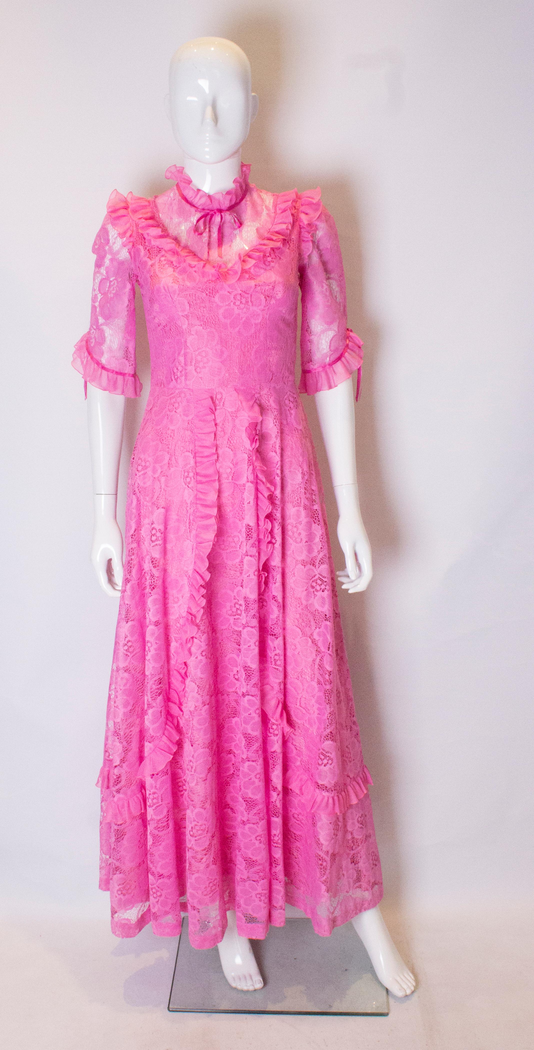 A stunning dress in pink lace. The dress which is fully lined with a central back zip has elbow length sleaves  with a ribbon detail.  It has a flared skirt with frills and ribbon detail.