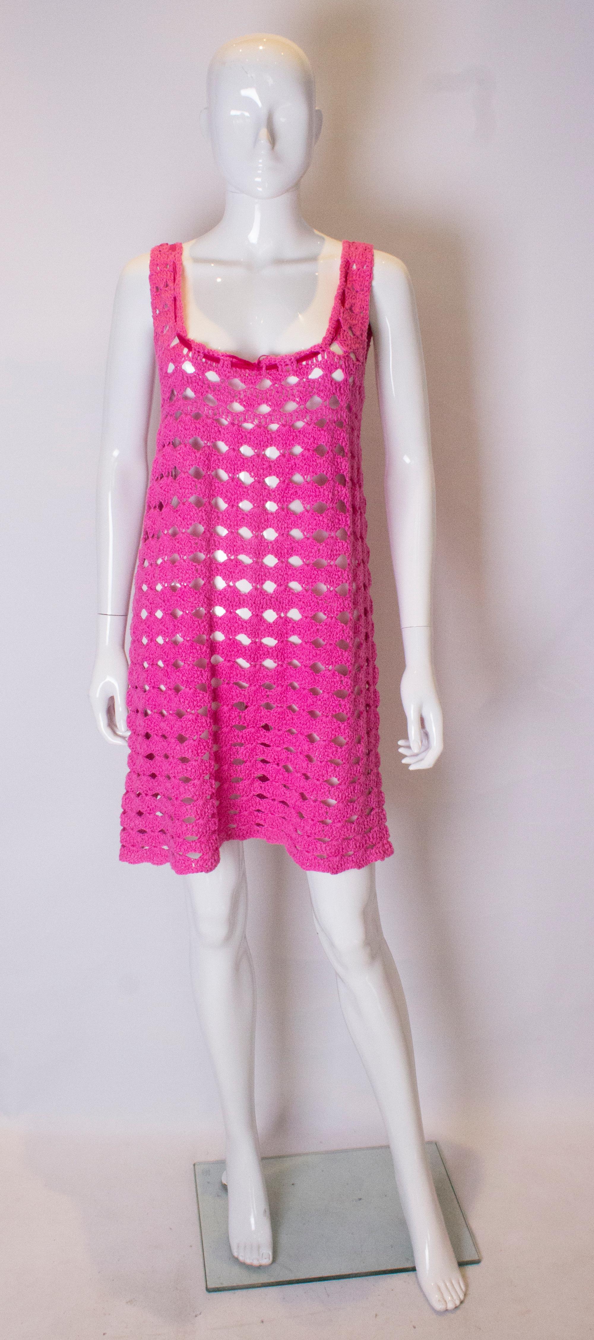 A pretty vintage pink crochet dress. The dress has a scoop neckline and backline with ribbon detail , and an A line flare.