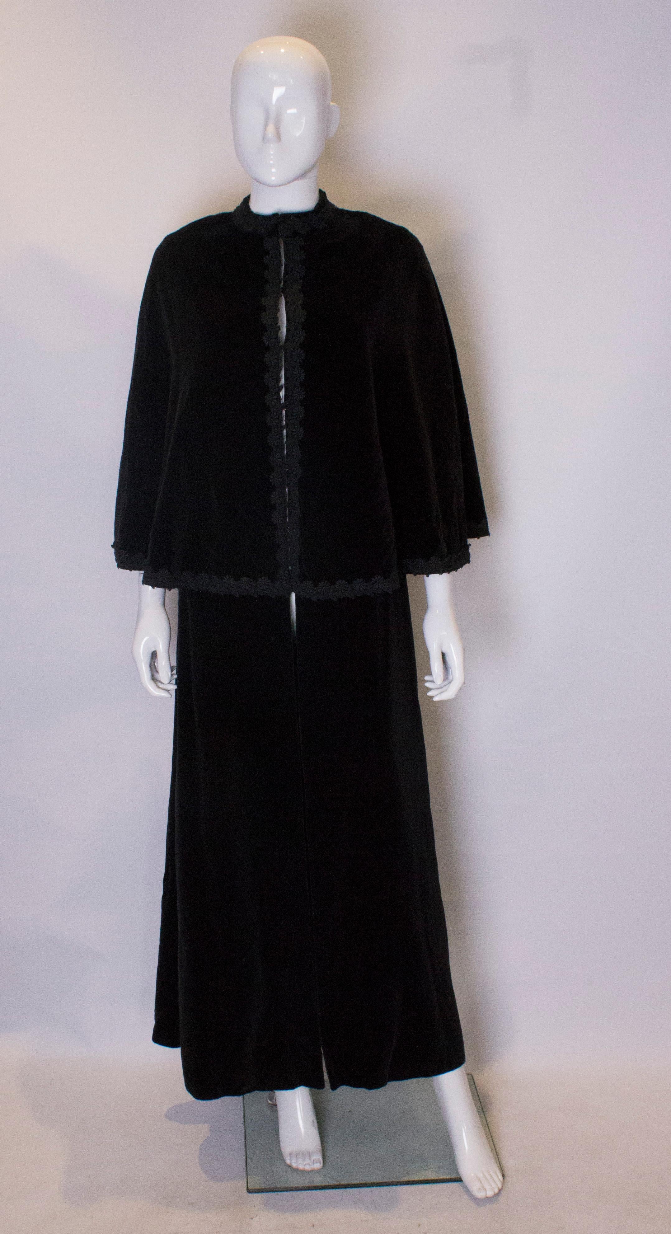 A stunning vintage cape for fall /winter, The cape has an over capelet decorated with black braid.  It fastens centrally with hooks and eyes.There are arm holes under the capelet., and it fully lined.