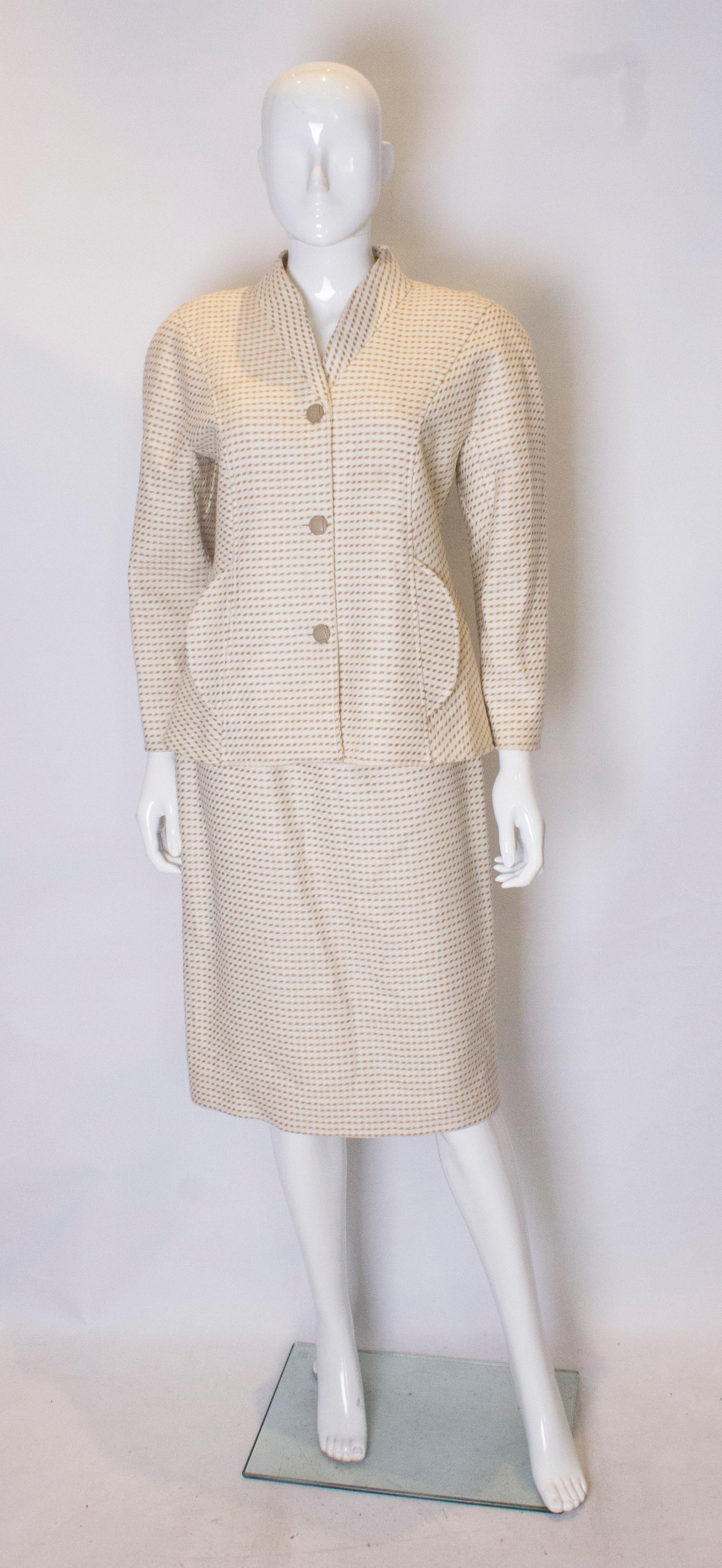 A chic  vintage wool skirt suit by Courreges. The jacket is wonderfully tailored, and has a three button central opening and two pockets at the front.  The fabric has an ivory background with olive colour detail. The skirt fits smoothly over the