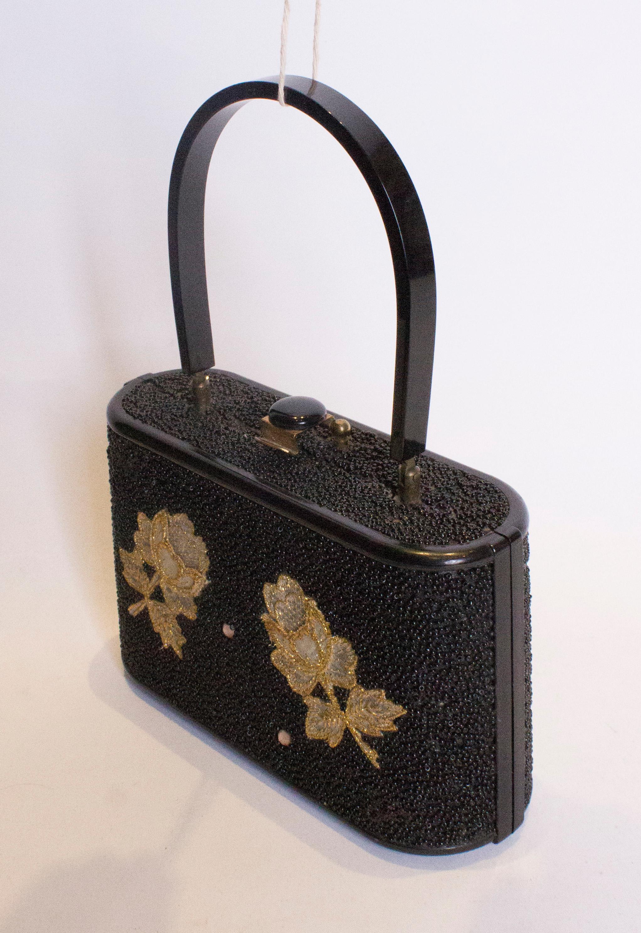 A stunning beaded bag with floral fabric decoration.The bag has a top handle and central top opening.
Measurements: width 9'', height 5 1/4'' , depth 3''