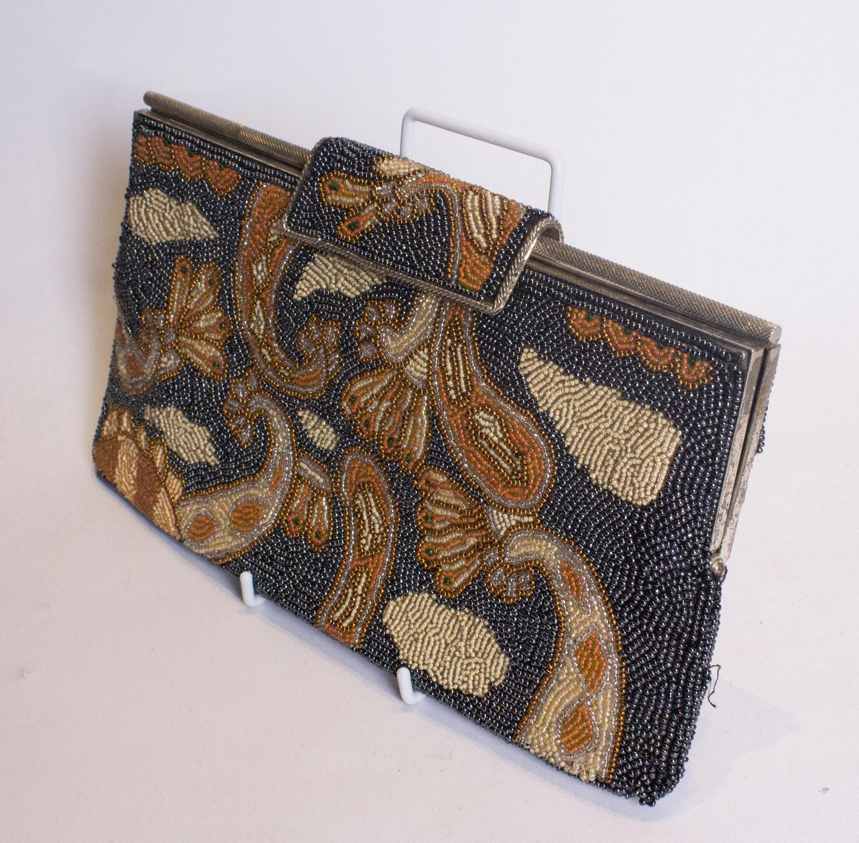 A chic vintage  beaded bag.  The beads are in grey, orange and yellow in an attractive pattern. The bag has a fold over clasp and is lined with one pouch pocket,. Measurements: width 11''. height 6'',depth 1''