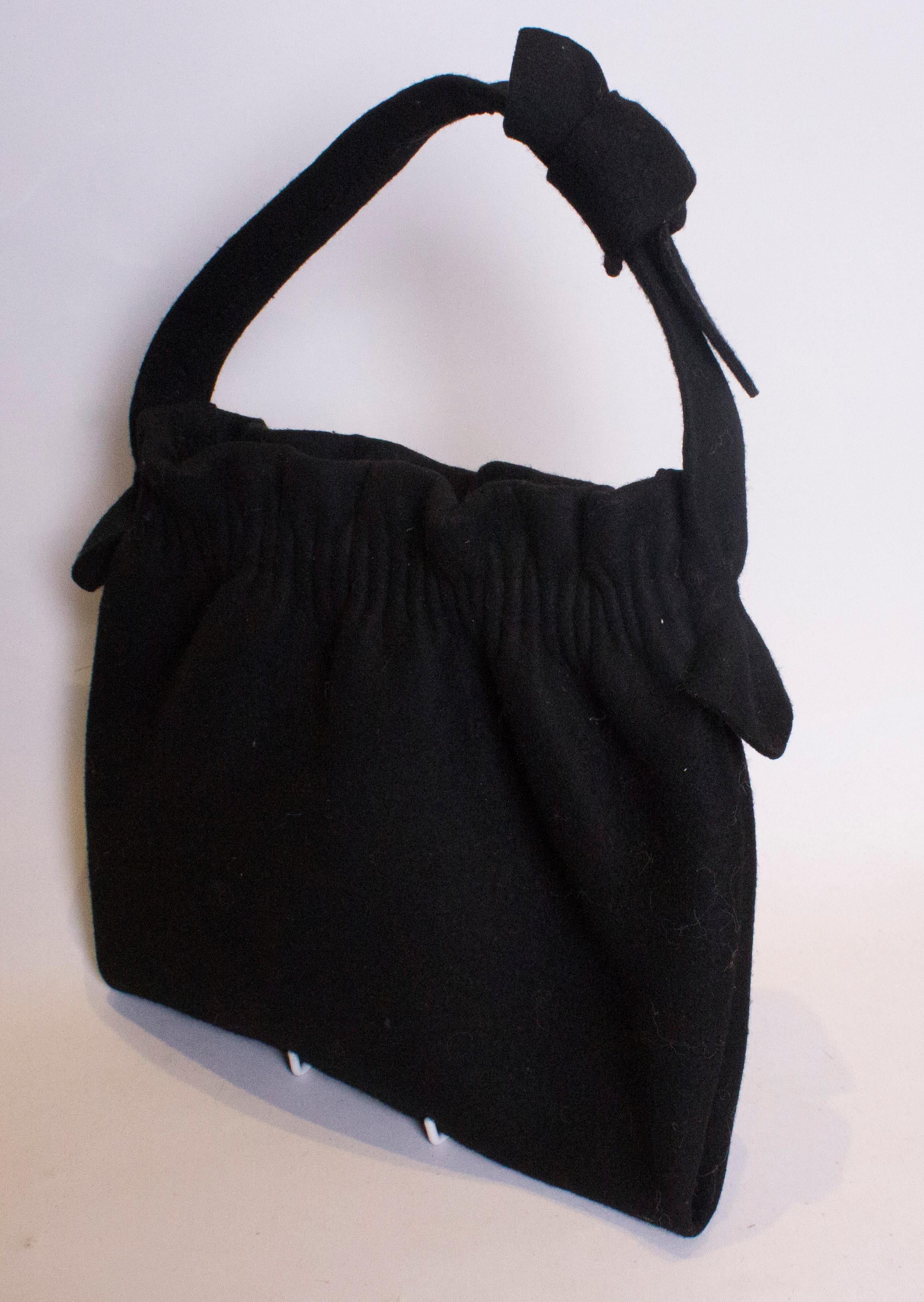 A cut vintage black felt bag that is large enough for todays essentials. The bag has gathering at the top, and is top handle.
Measurements: width 11  1/2'', height 11'' depth 1 1/2''