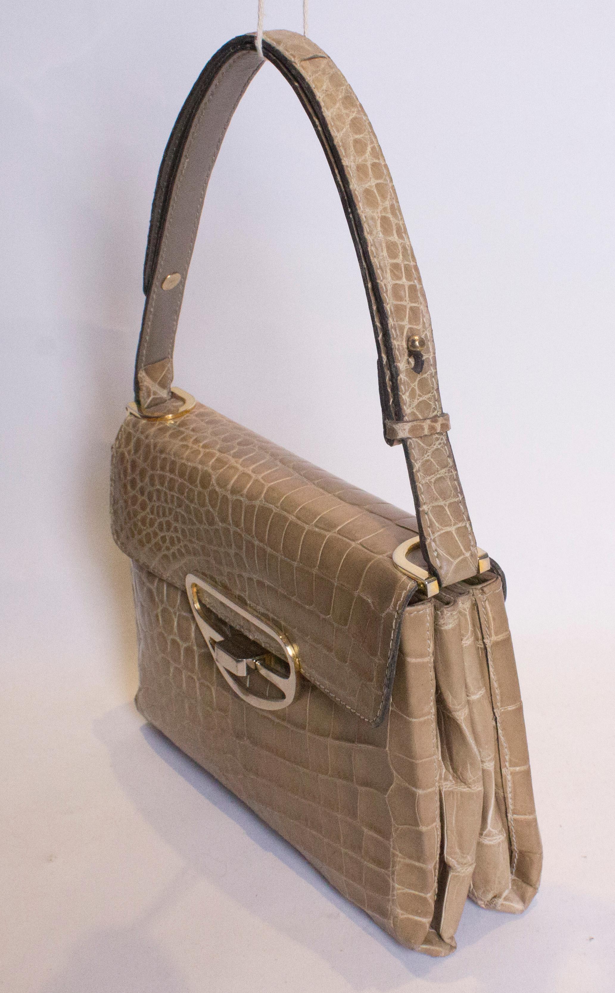 A chic biscuit colour crocodile bag  with adjustable strap and so can be either a handbag or shoulder bag. Internaly there are two pouch pockets. Measurements: width 10'', height 7'', depth 3'